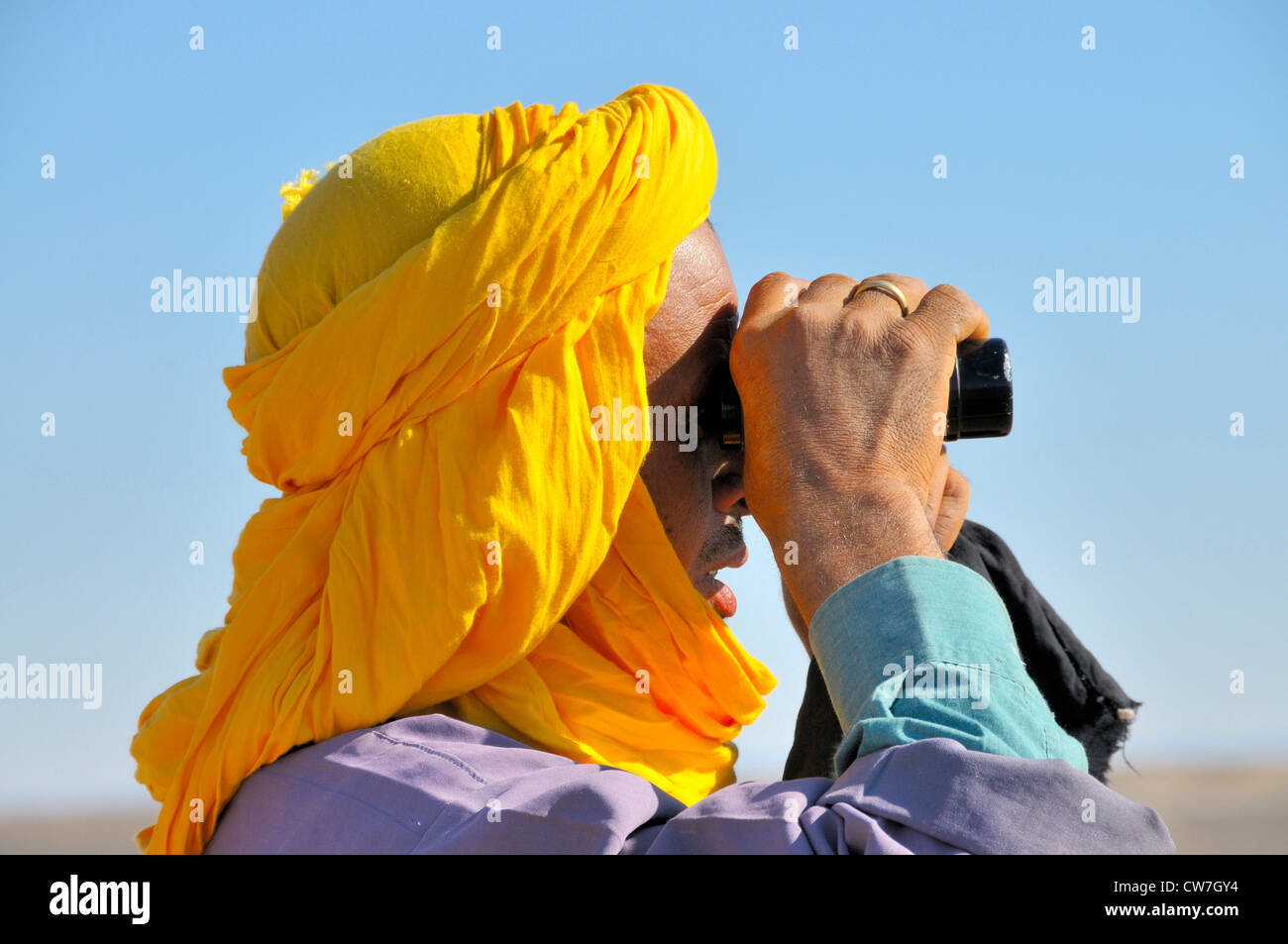 Berber mit traditionellen Tagelmust, die auf der Suche nach verlorenen Tiere mit einem Fernglas, Marokko, Erg Chebbi, Sahara Stockfoto