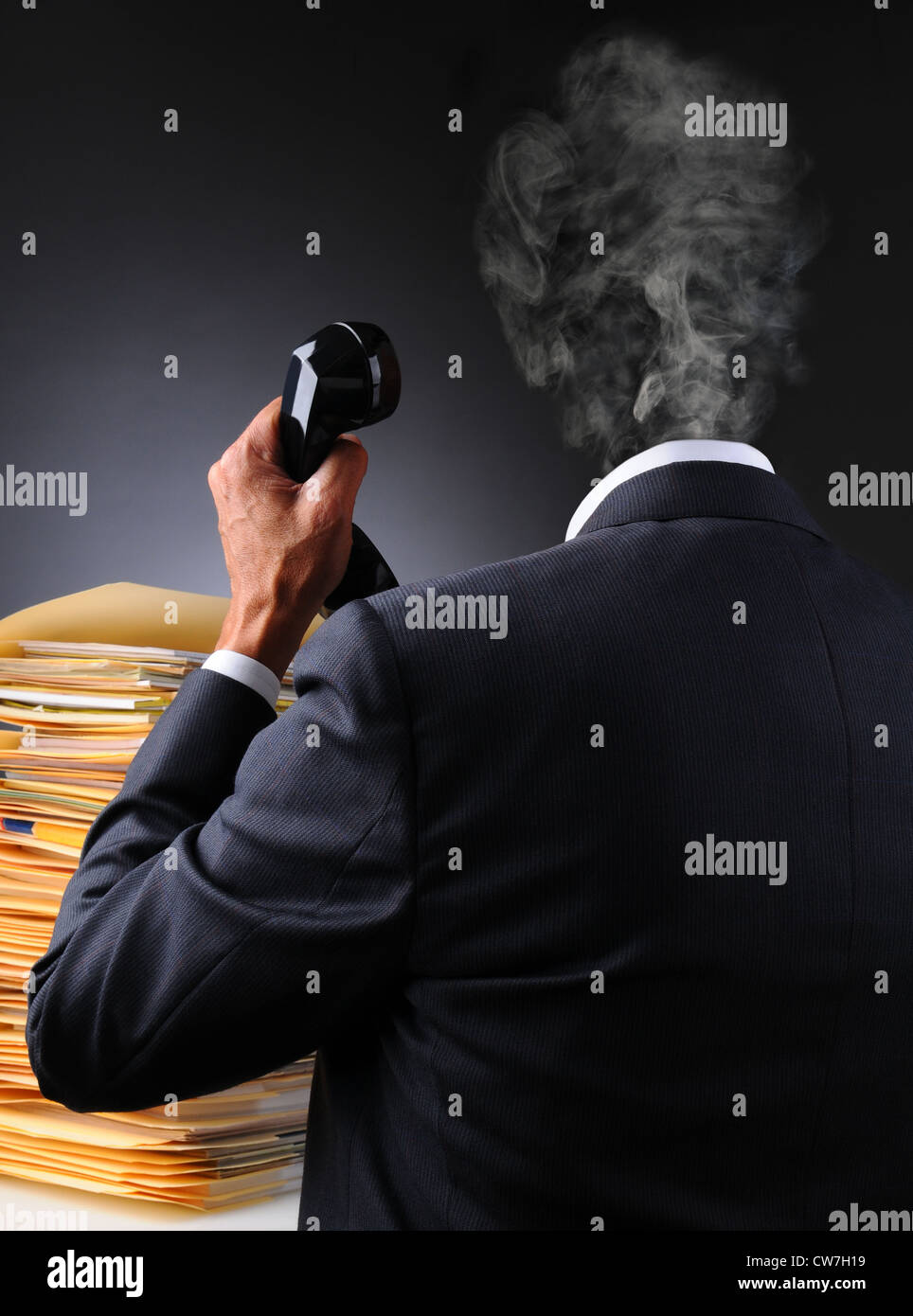 Ein gestresster Geschäftsmann mit Dateien und Telefon als sein Kopf explodiert in einer Rauchwolke. Stockfoto