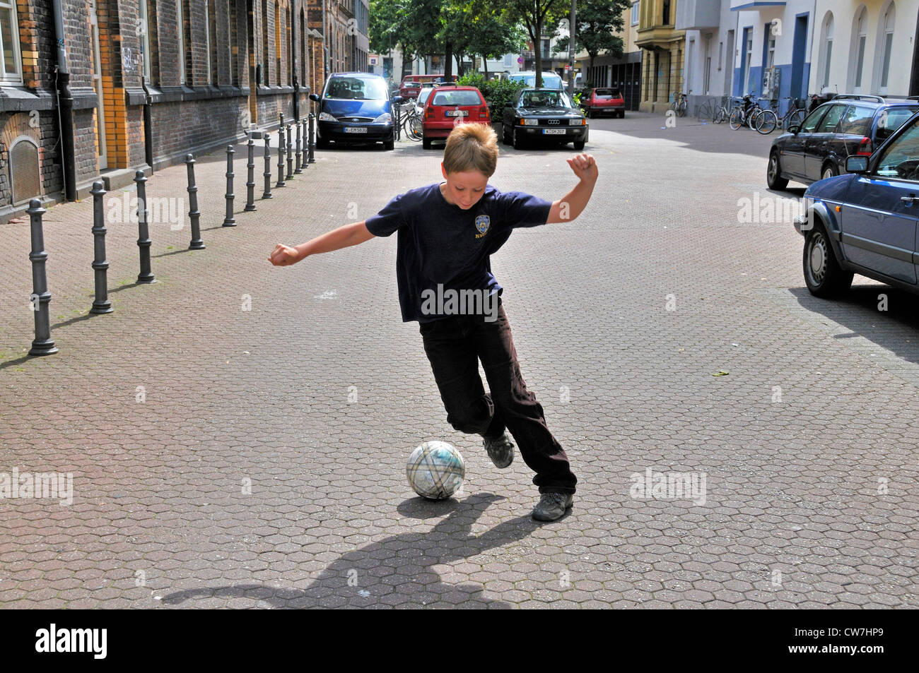 zehn Jahre alten Jungen spielen Fußball auf der Straße, Deutschland Stockfoto