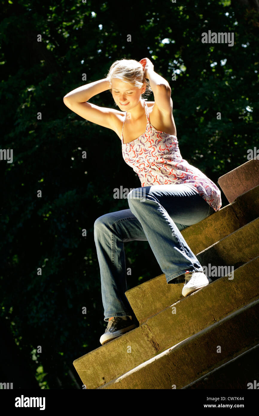 junge Frau in Freizeitkleidung sitzt auf der Treppe Stockfoto