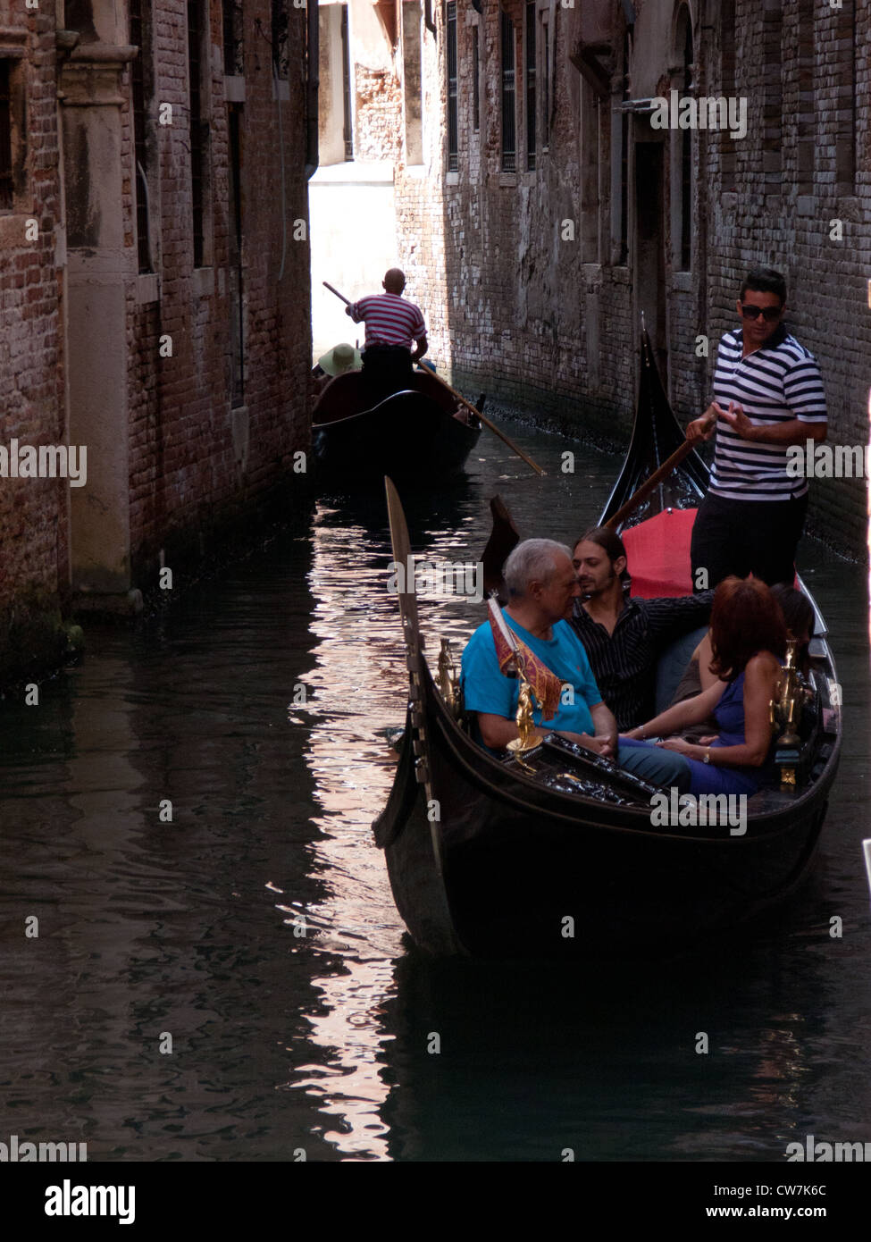 Touristen genießen eine Gondelfahrt auf einem Kanal in Venedig, Italien Stockfoto