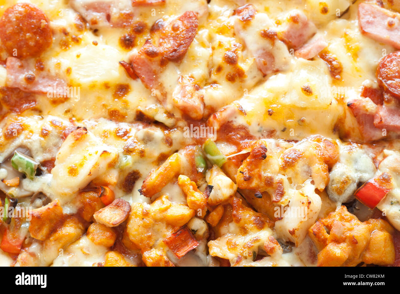 Pizza mit Wurst, Schinken, Hühnerfleisch, Paprika, Ananas auf einem weißen Teller. Stockfoto
