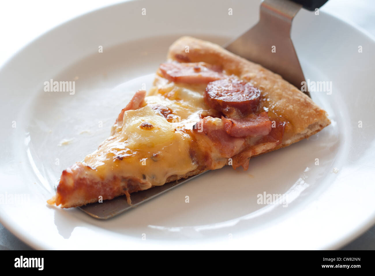 Pizza mit Wurst, Schinken, Hühnerfleisch, Paprika, Ananas auf einem weißen Teller. Stockfoto