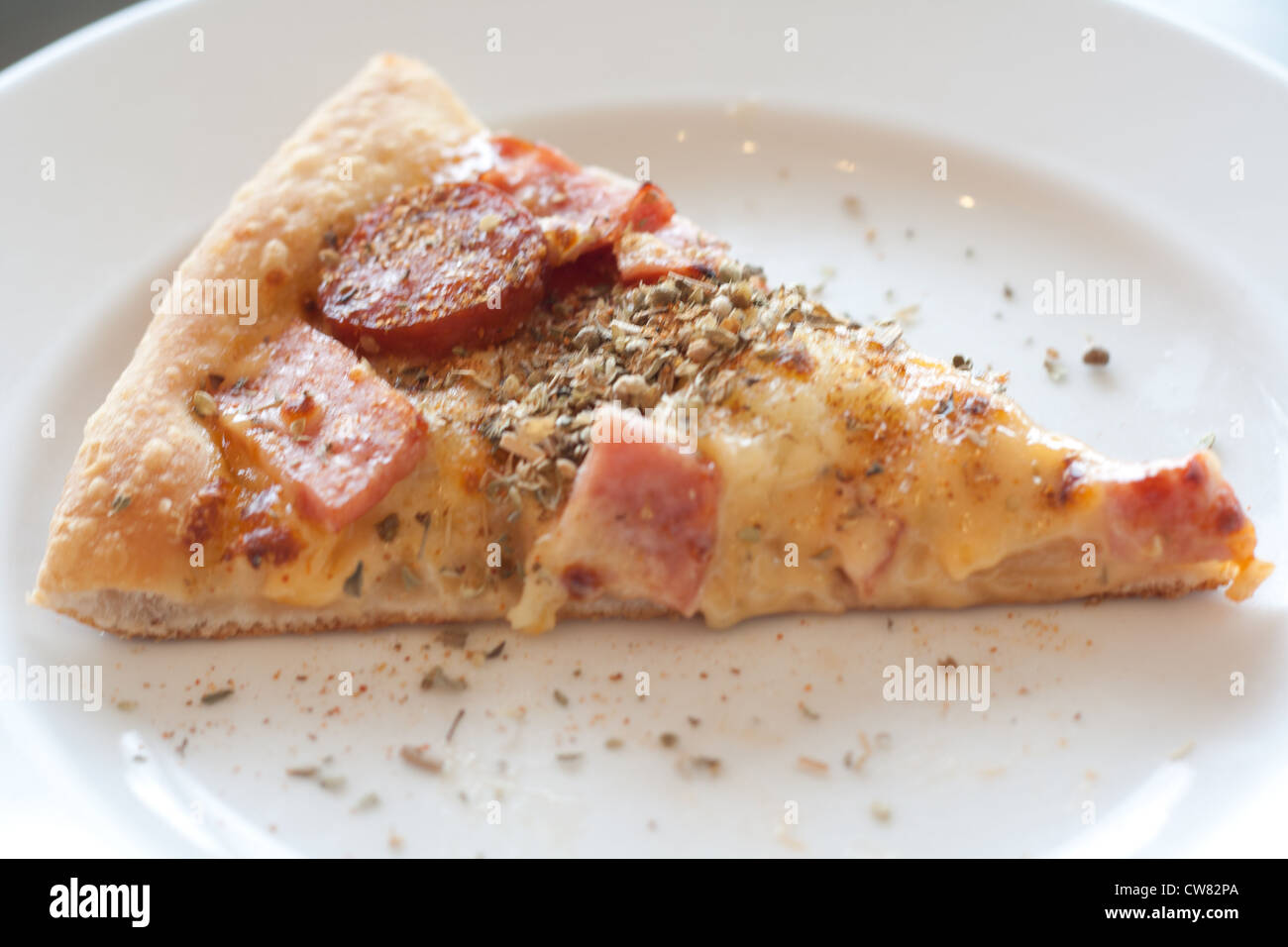 Pizza mit Wurst, Schinken, Hühnerfleisch, Paprika, Ananas auf einem weißen Teller. Stockfoto