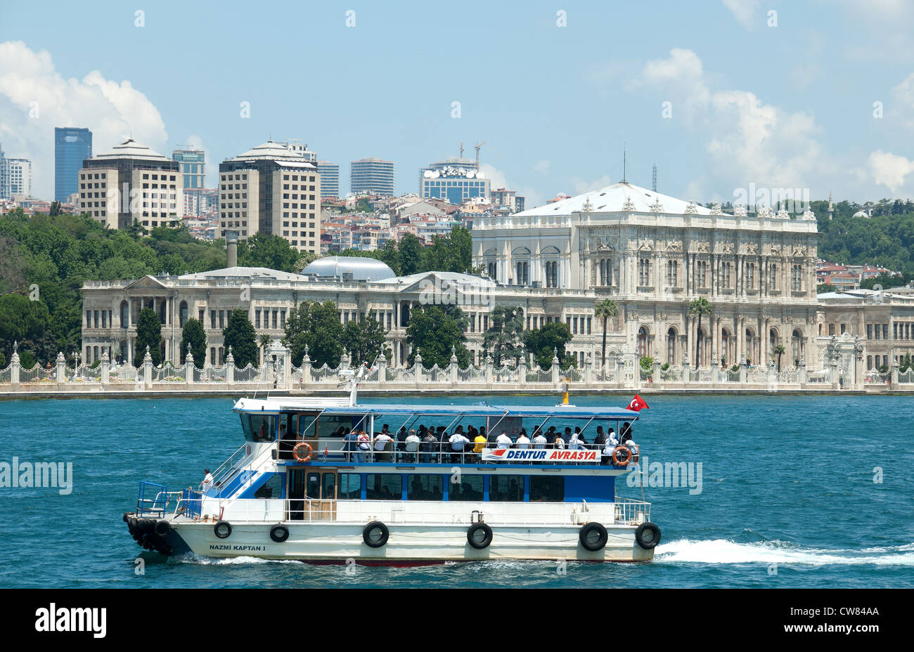 ISTANBUL, TÜRKEI. Ein Ausflugsschiff auf dem Bosporus mit den Dolmabahce Palast und die moderne Stadt hinter. 2012. Stockfoto