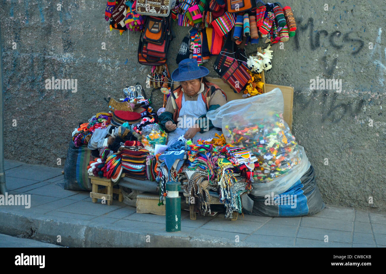 La Paz, die höchstgelegene Hauptstadt der Welt auf 3700m. Bolivien, Südamerika. Inca-Frau sitzt auf Asphalt mit Stricken Stockfoto