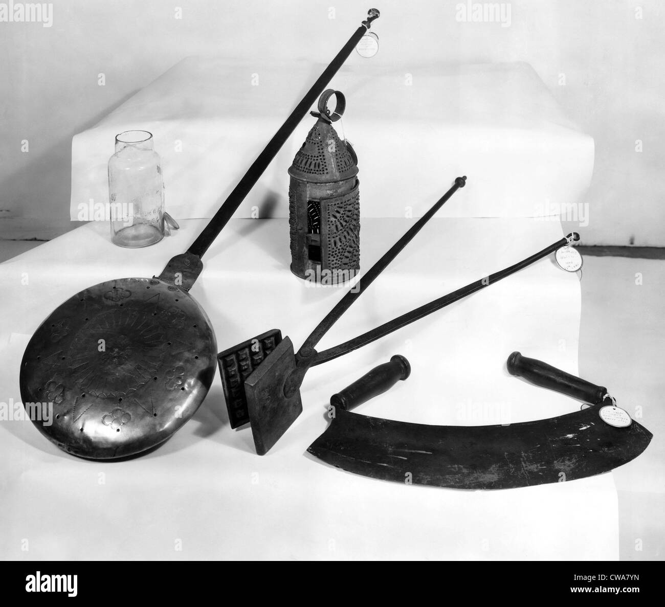 Geschirr, frühen amerikanischen Haushaltsgeräten, l-r: Obst Glas, Messing-Bett wärmer, Town Crier Laterne (zurück), antike Waffel Stockfoto