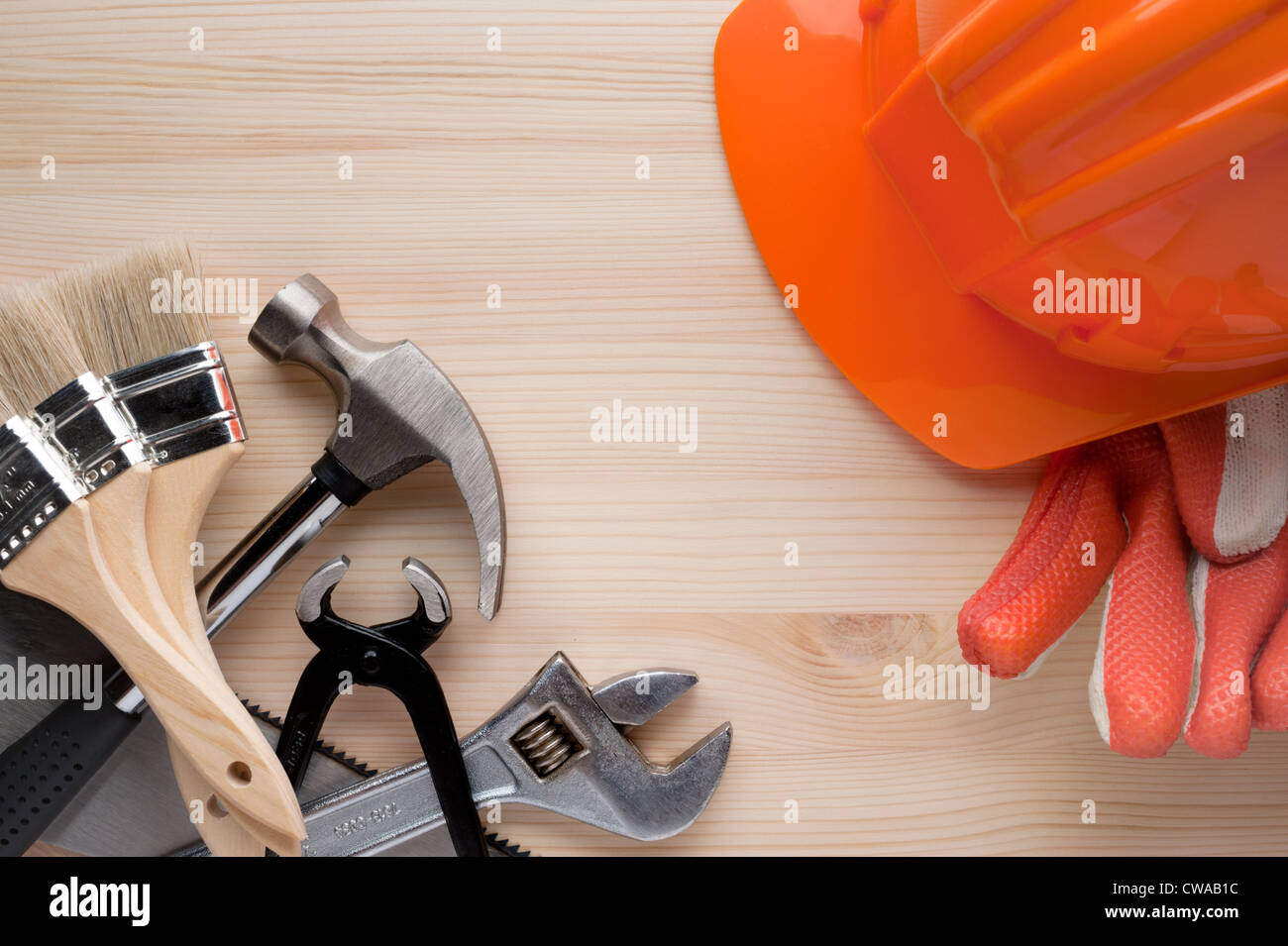 Bauarbeiterhelm, verschiedene Handschuhe und einige Werkzeuge, die auf einer Holzfläche angeordnet. Bau, Reparatur oder zu Hause Verbesserung Hintergrund. Stockfoto