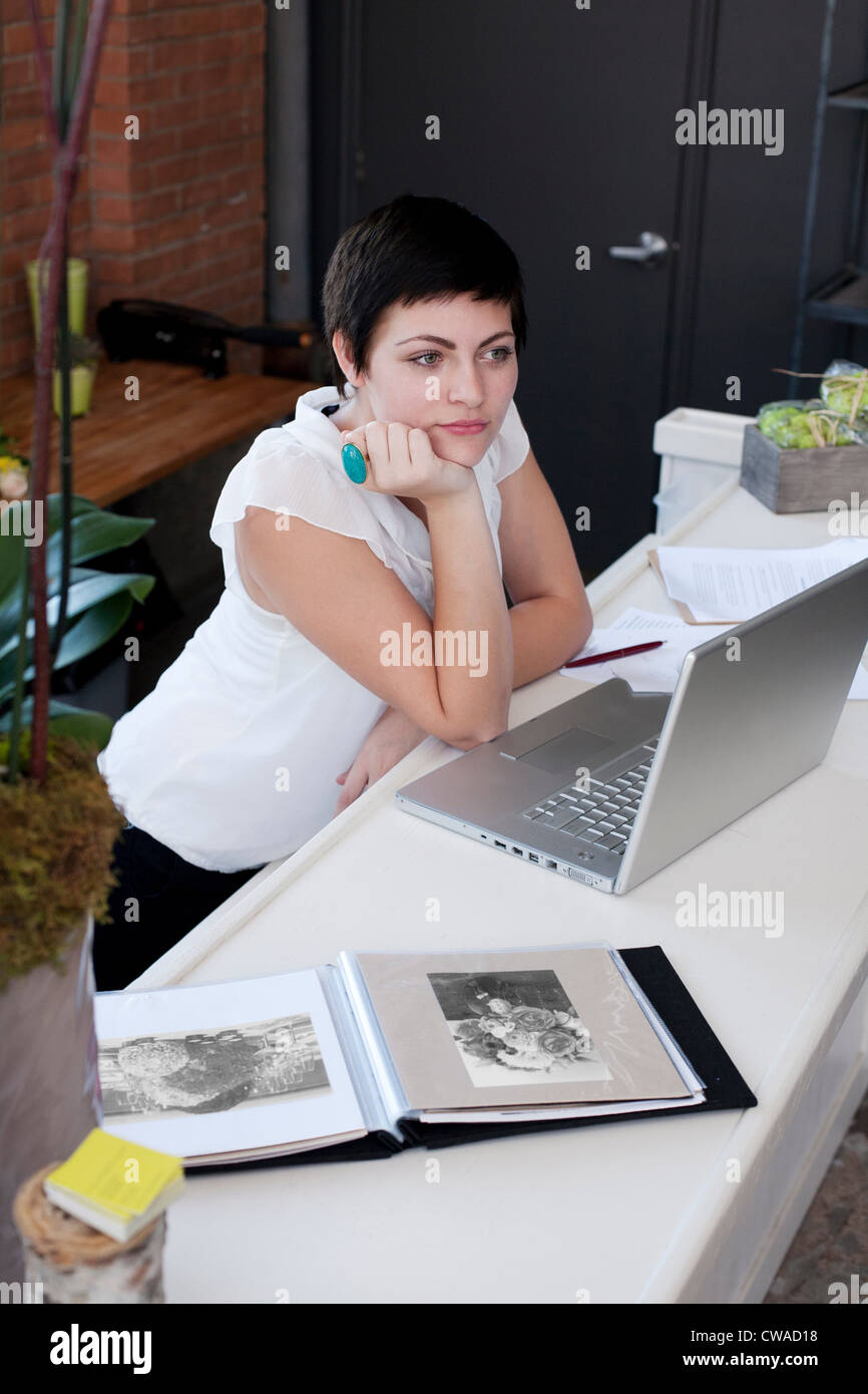 Geschäftsfrau am Schreibtisch mit Hand am Kinn Stockfoto