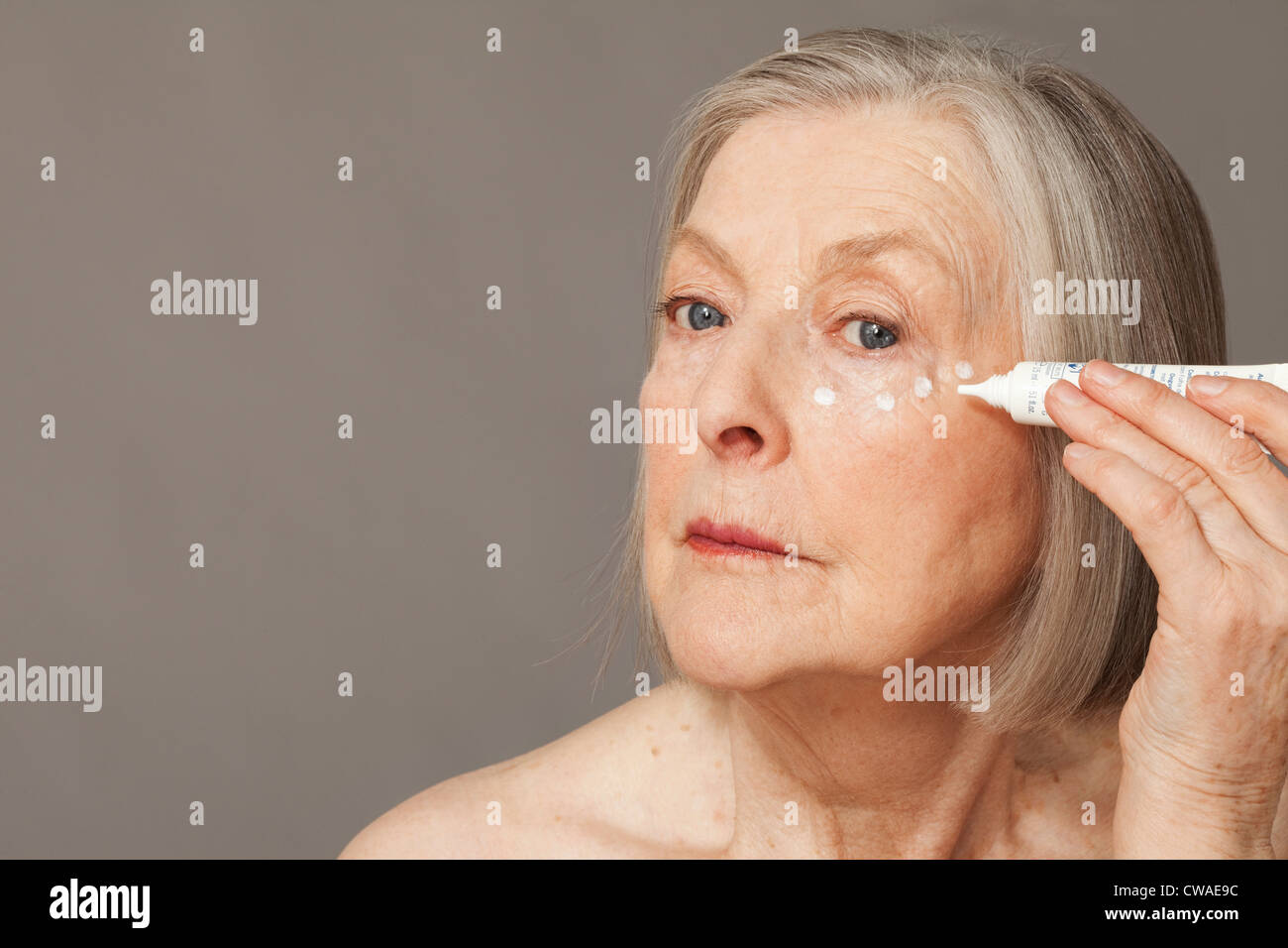 Ältere Frau Augencreme anwenden Stockfoto