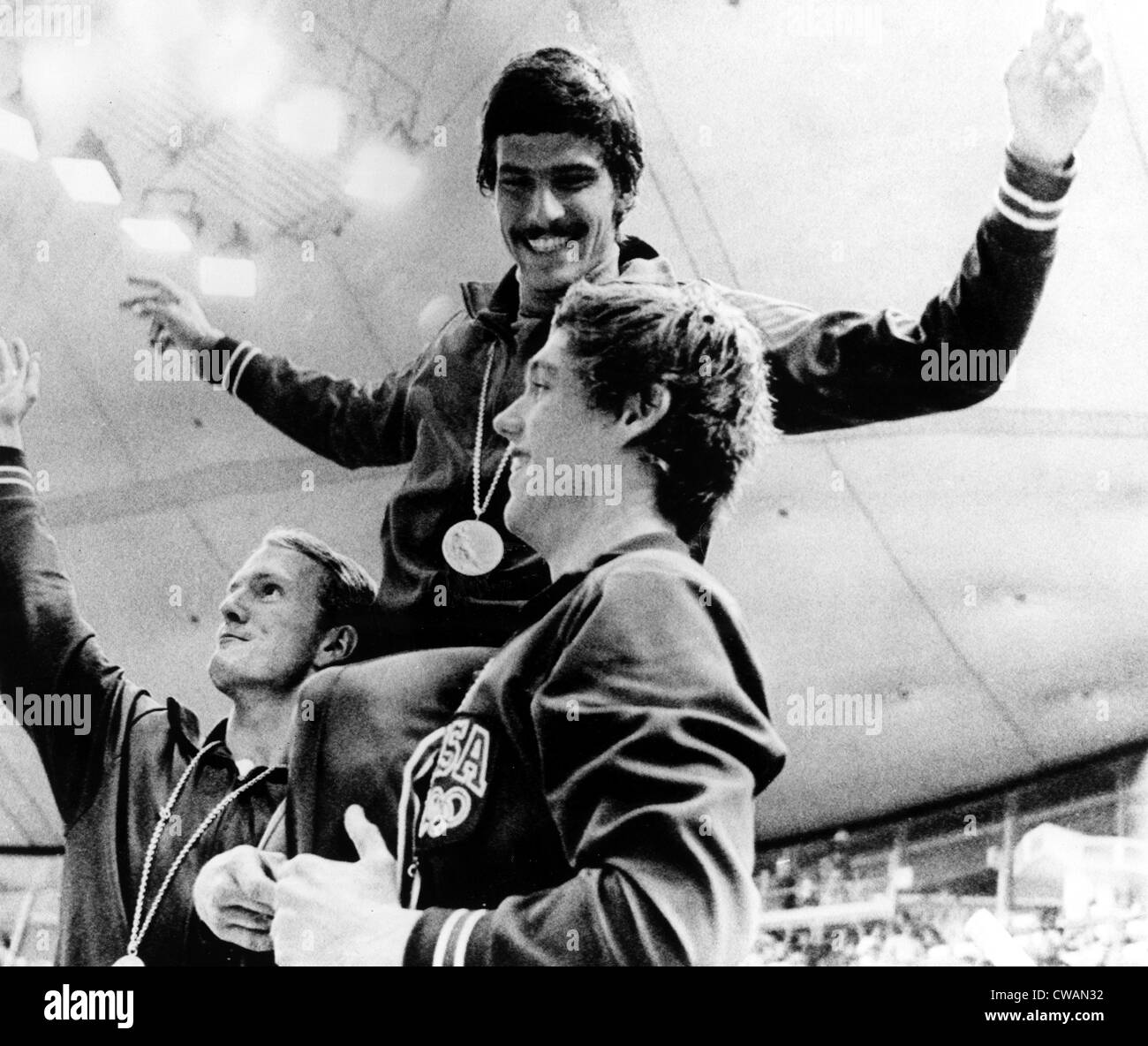 Mark Spitz zeigt seine 7. Goldmedaille, unterstützt von Teamkollegen Tom Bruce (L) und Mike Stamm (R), nach dem Sieg der USA im Stockfoto