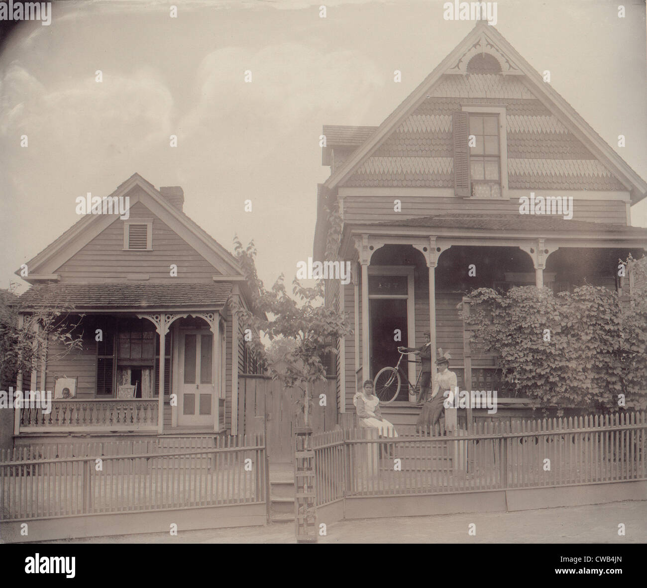 African American Boy sitzt auf der Veranda des Hauses, einem anderen afroamerikanischen jungen stehend mit dem Fahrrad auf der Veranda eines anderen Hauses, Stockfoto