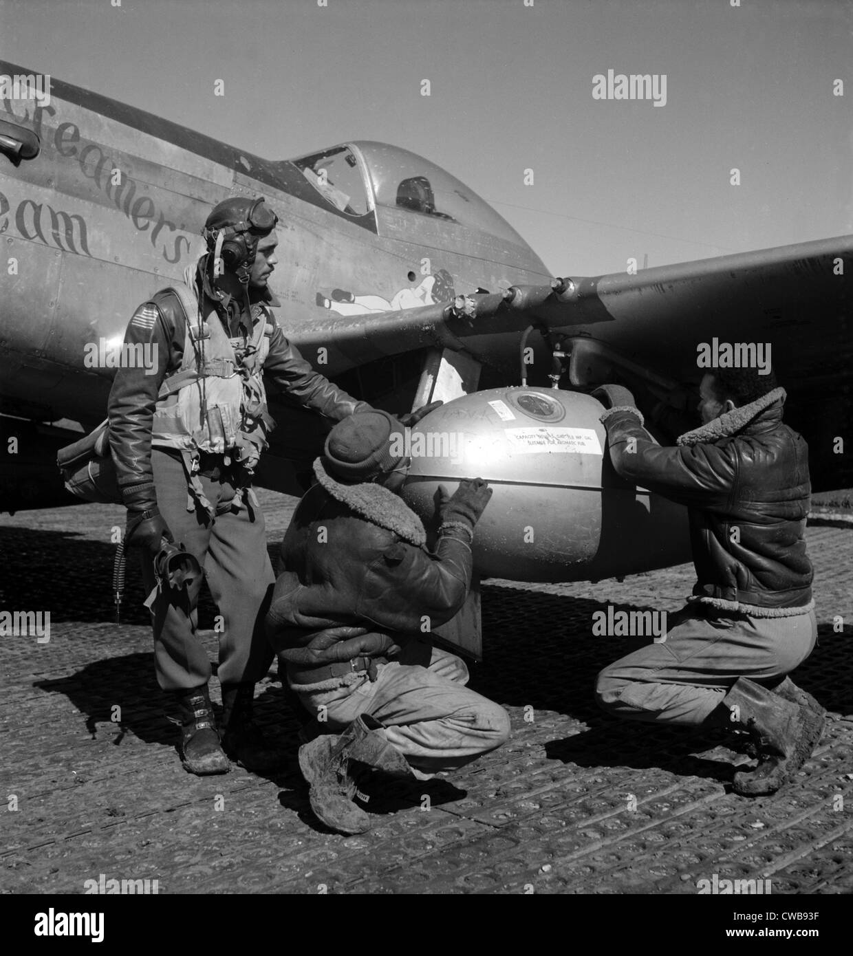 Tuskegee Kampfpilot und zwei Flieger, die Einstellung eines externen 75 Gallone Drop Tanks auf dem Flügel von einer P - 51D Mustang Stockfoto