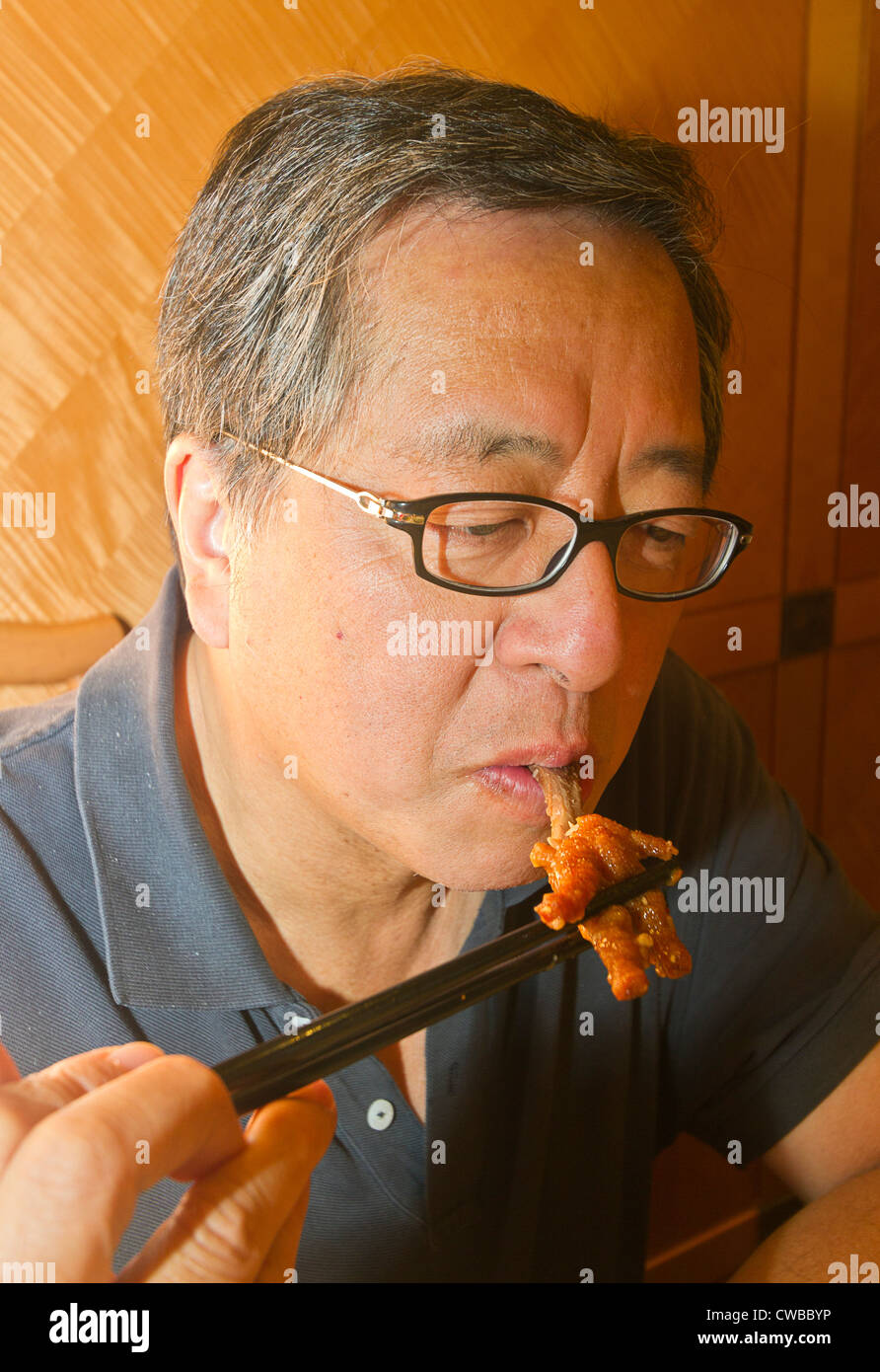 Asiatischer Mann isst Hühnerfüße, beliebtes Gericht für Dim Sum serviert chinesische Brunch. Stockfoto