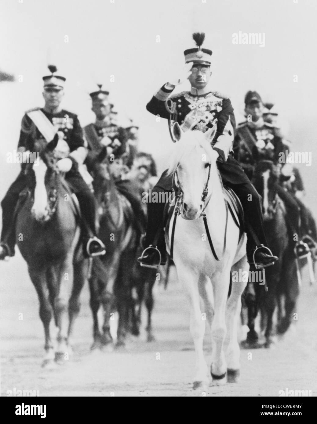 Japans Kaiser Hirohito, auf dem Pferderücken in Militäruniform, mit Gruppe von japanischen Offiziere salutieren. Ca. 1940. Stockfoto