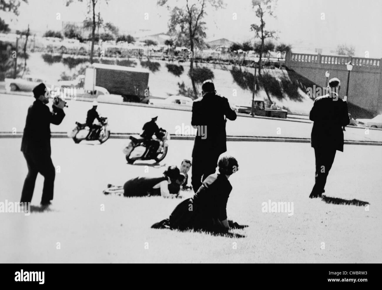 Sekunden nach Kennedys Ermordung zwei Polizisten auf Motorrädern durch beschleunigen, wie einige Zuschauer auf den Boden kauern, Stockfoto