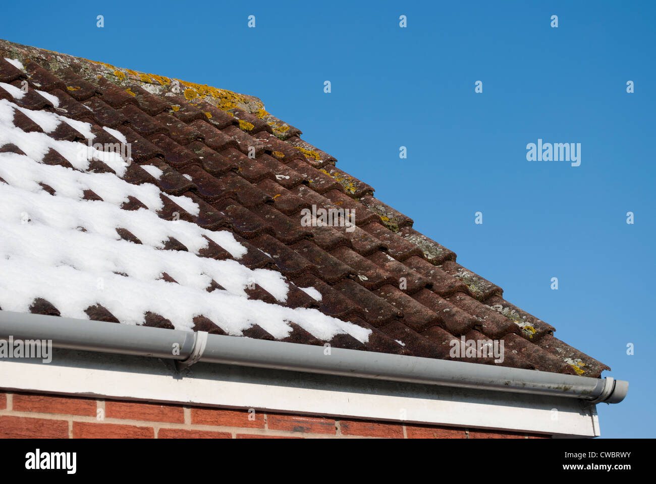 Ende des geneigten Dach teilweise schneebedeckt vor tiefblauem Himmel Stockfoto