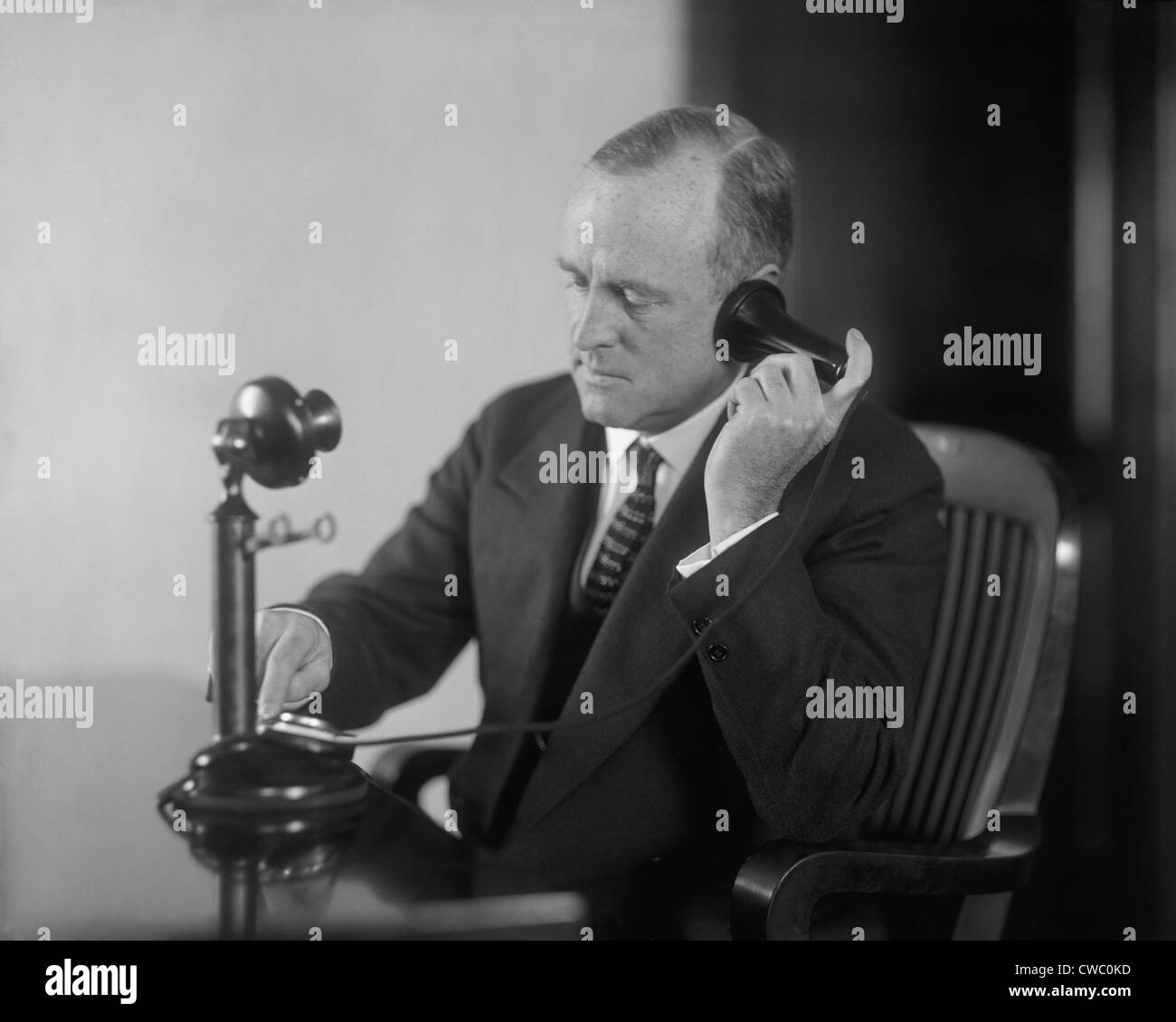 Geschäftsmann, eine Anfang des 20. Jahrhunderts Tischtelefon mit separaten Ohr Empfänger und Mund Sender wählen. Ca. 1920. Stockfoto