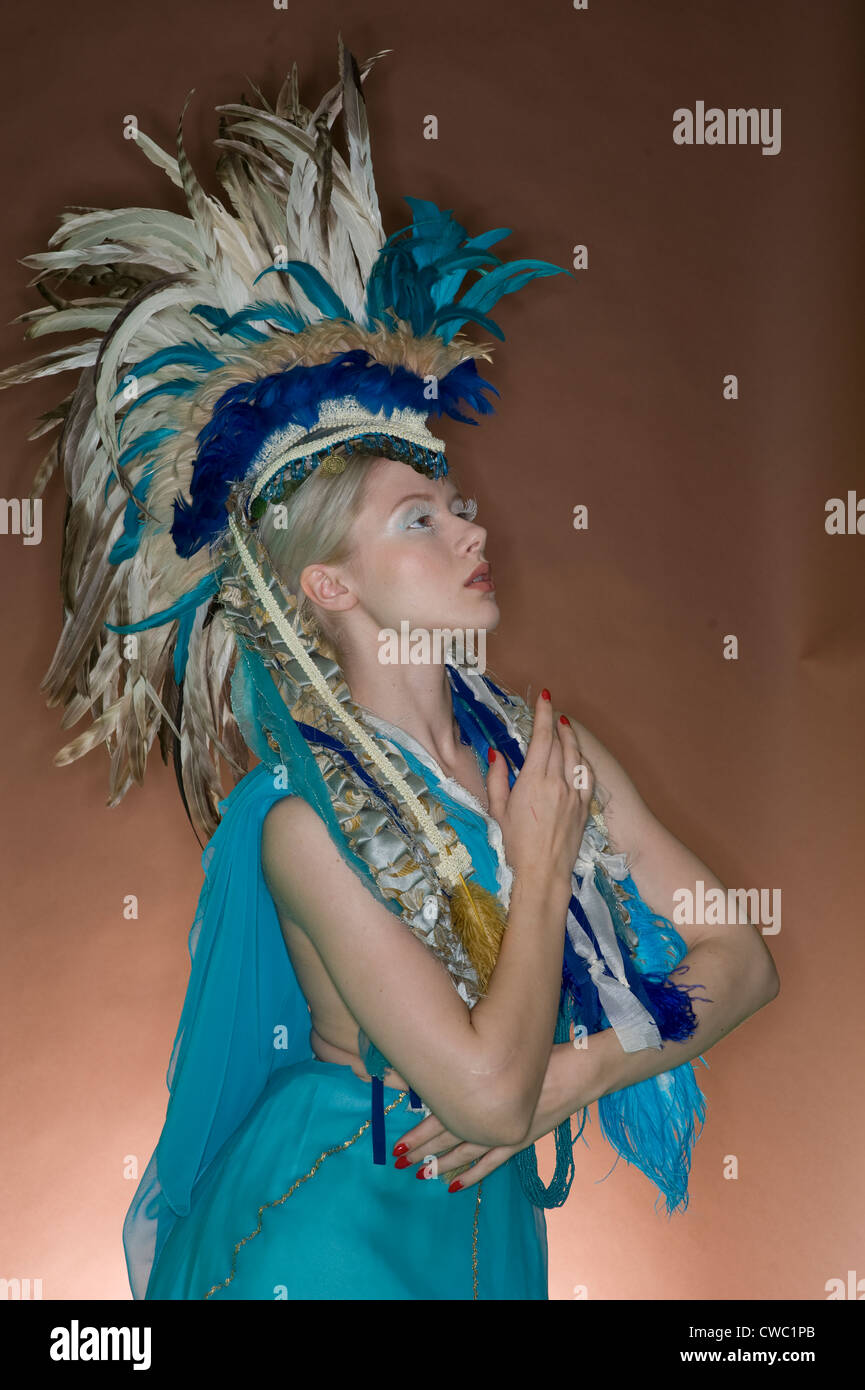 Schöne Frau posiert in gefiederten Outfit über farbigen Hintergrund Stockfoto