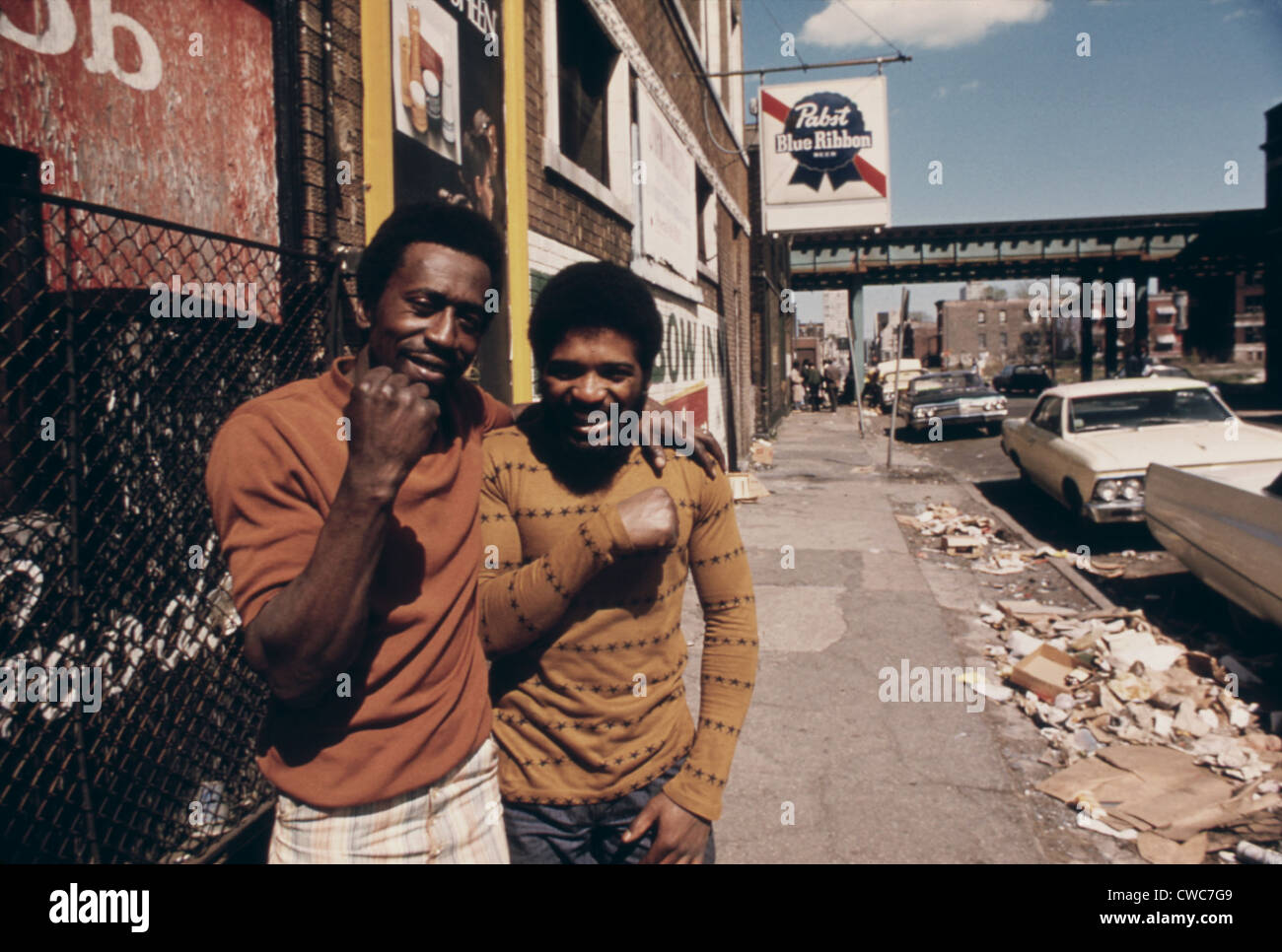 Lächelnd afroamerikanische Männern in einer Müll übersäten Straße auf der South Side von Chicago. Ca. 1975. Stockfoto