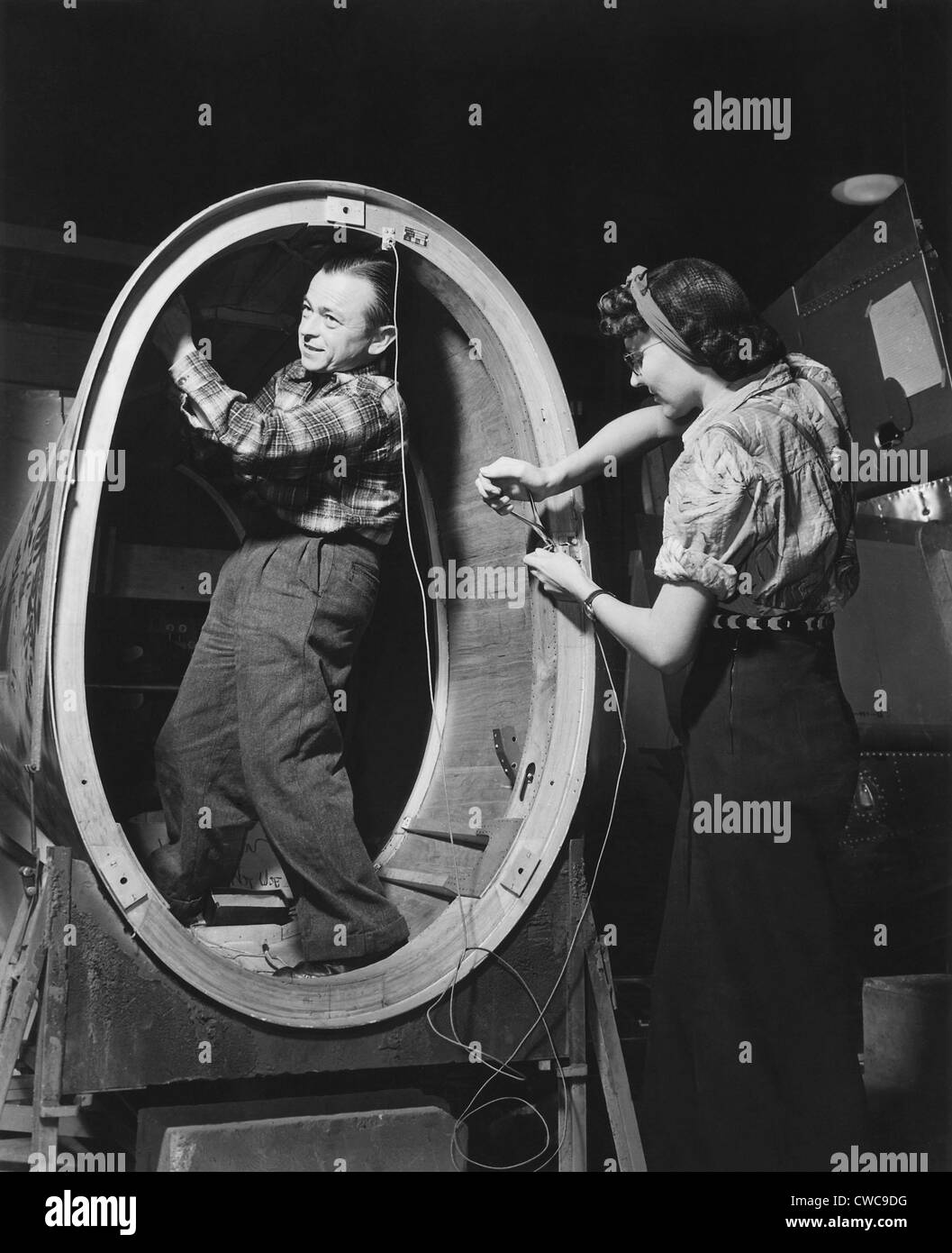 Ein kleiner Mann installiert Steuerleitungen im Rumpf der "Valiant" grundlegende Trainer, während eine Frau außerhalb arbeitet. Stockfoto