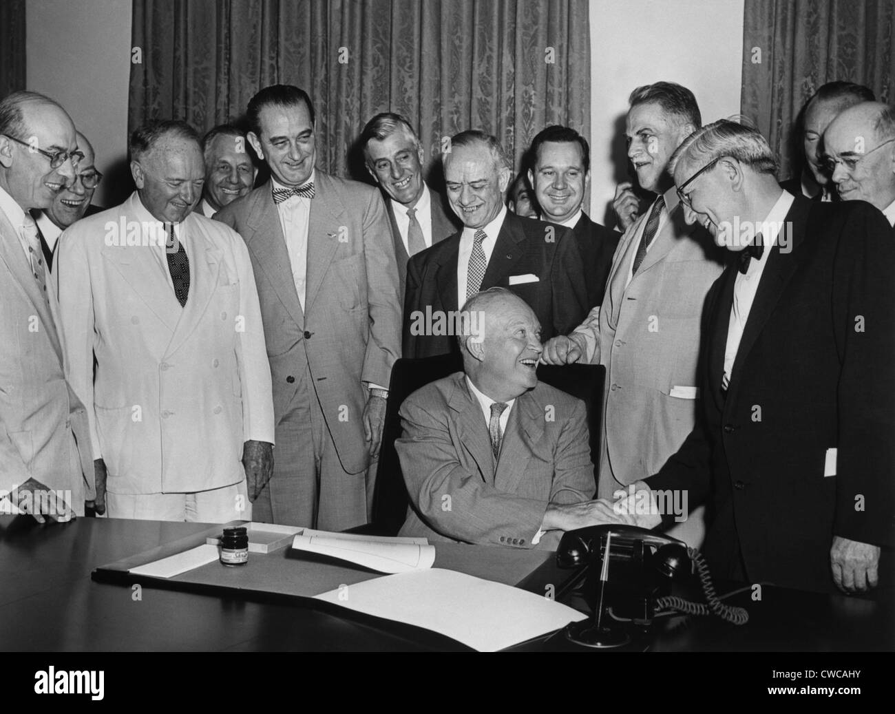 Präsident Eisenhower unterzeichnet eine Rechnung als Mehrheitsführer im Senat, Lyndon b. Johnson, und andere mit Blick auf. Johnson ist fünfte von links Stockfoto