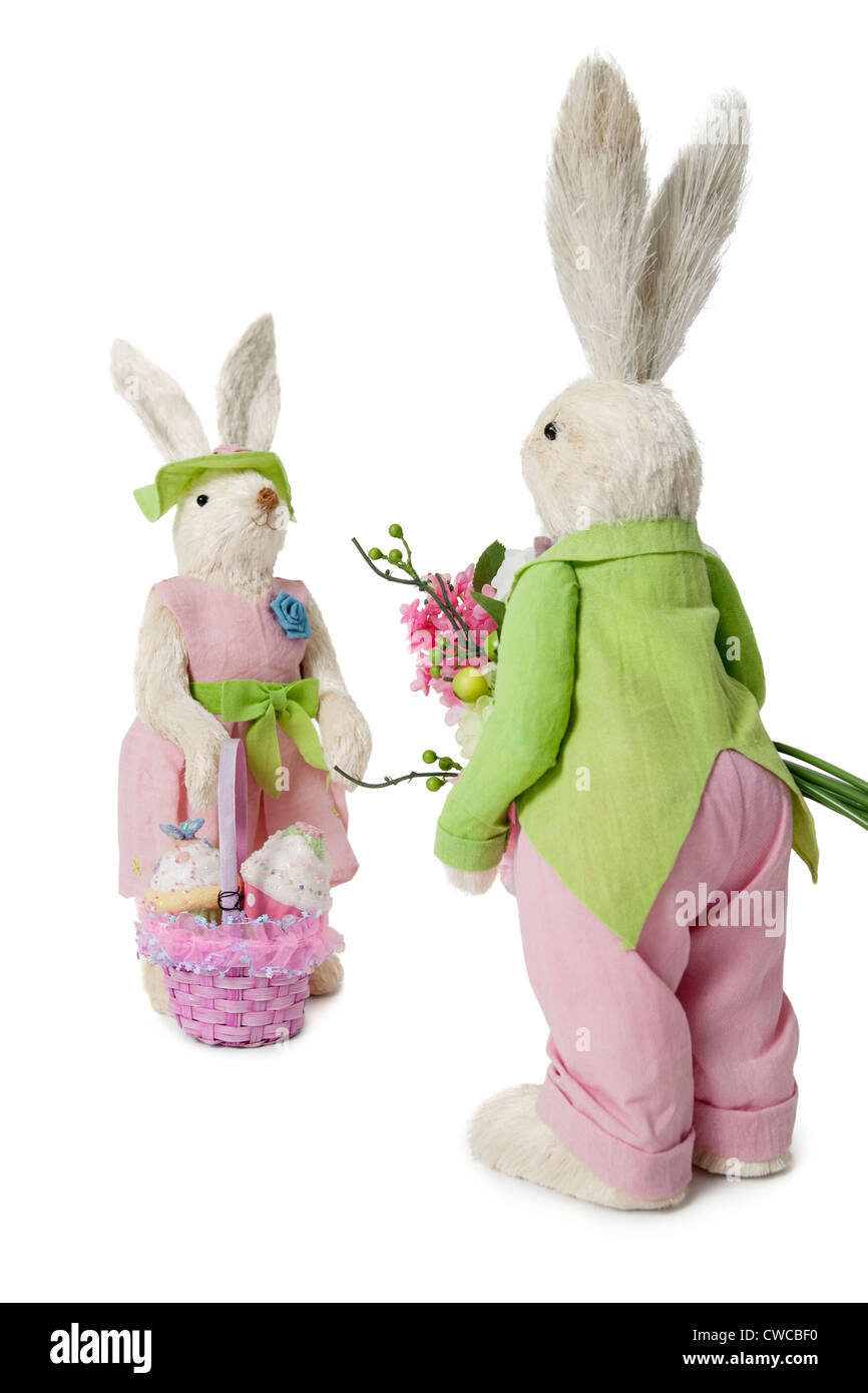 Männliche und weibliche Kaninchen mit Blumenstrauß und Korb auf weißem Hintergrund Stockfoto