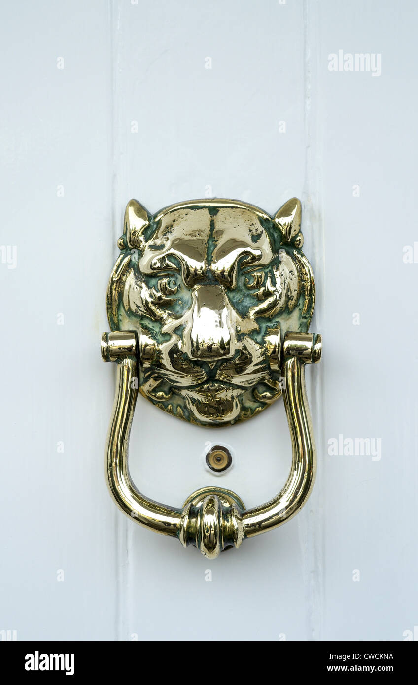 Messing poliert Türklopfer in Form eines Löwen Kopf auf eine weiße Tür mit Spion Loch Objektiv Stockfoto