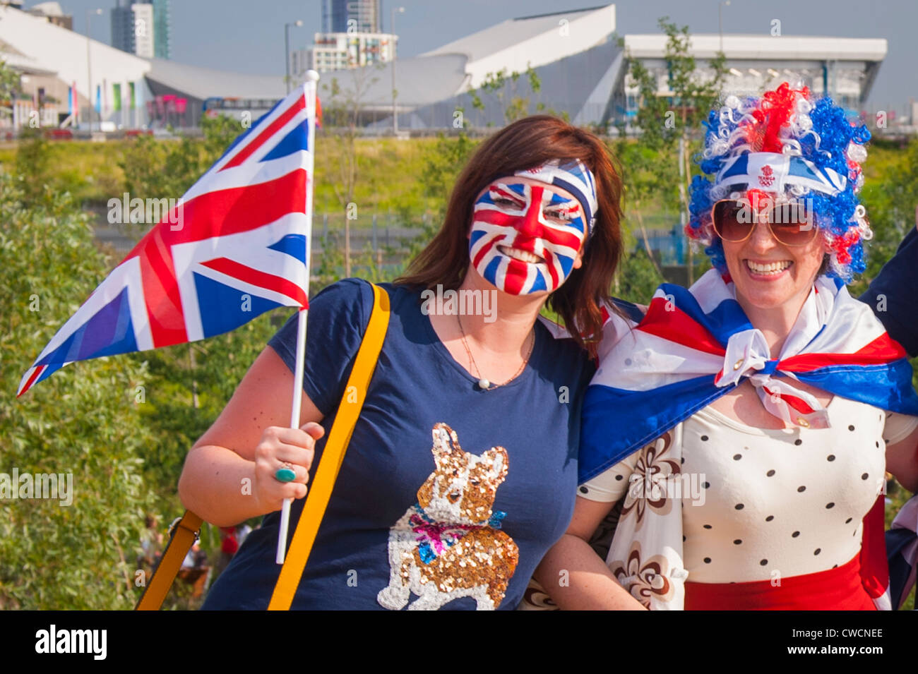 2012 in London, Stratford Olympic Park, Feiernden hübsche junge Mädchen Frauen Frauen mit Union Jack Flagge Flaggen Hut & bemaltem Gesicht Stockfoto