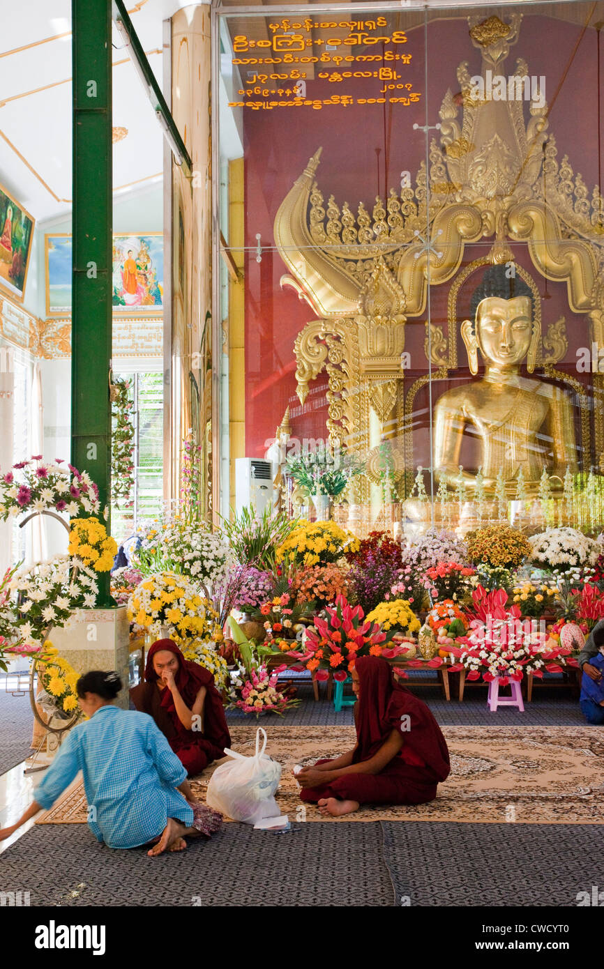 Myanmar, Burma. Junge Mönche in buddhistischen Schrein an Zayar Thein Gyi Nonnenkloster, in der Nähe von Mandalay. Buddha-Statue in Glas-Abdeckung. Stockfoto
