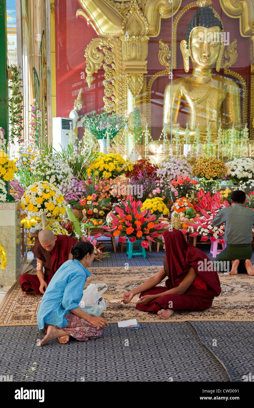 Myanmar, Burma. Junge Mönche in buddhistischen Schrein an Zayar Thein Gyi Nonnenkloster, in der Nähe von Mandalay. Buddha-Statue in Glas-Abdeckung. Stockfoto