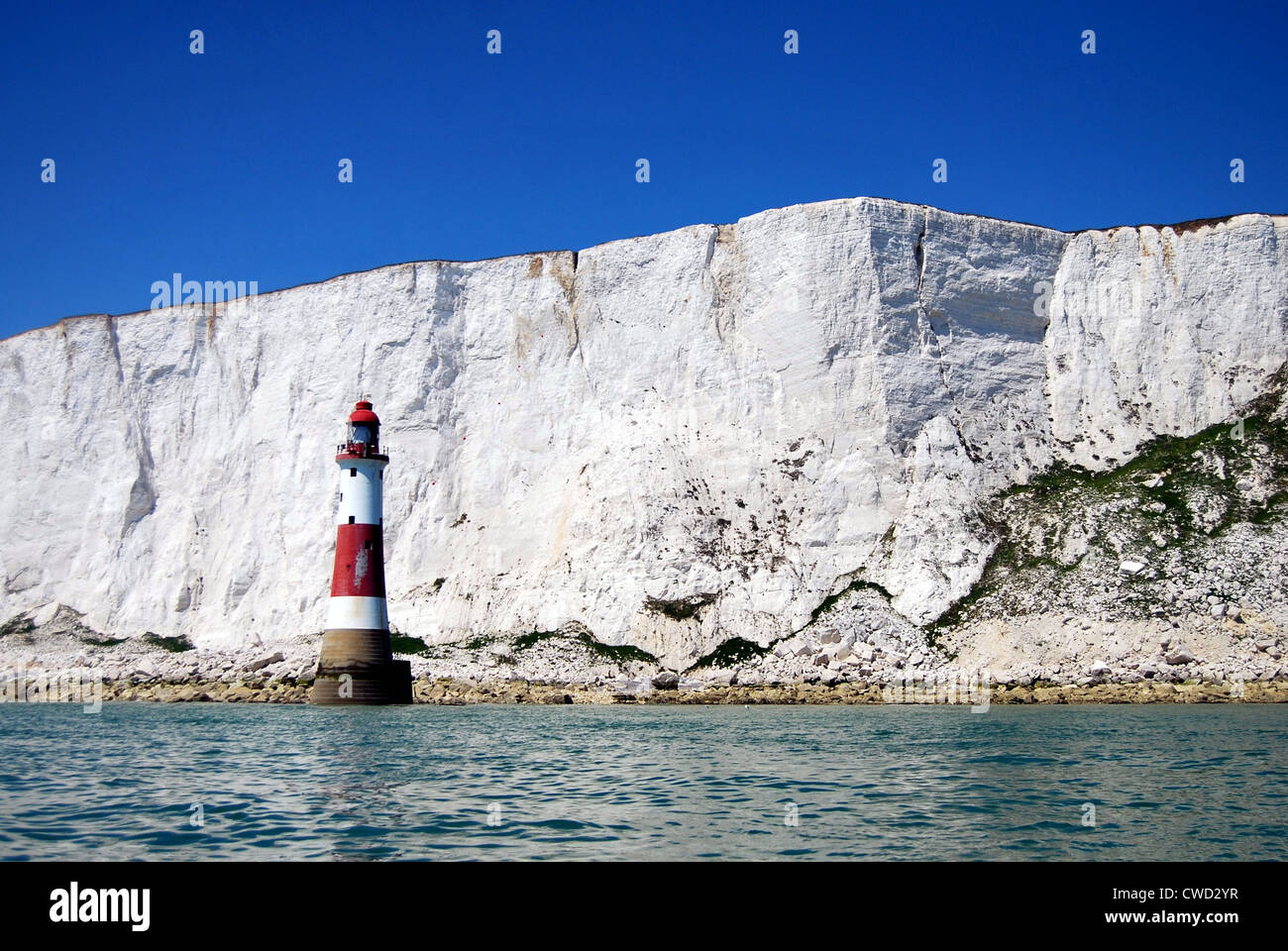 Ein Blick von Beachy Head Lighthouse aus dem Meer mit Klippen hinter mit blauem Himmel. Stockfoto