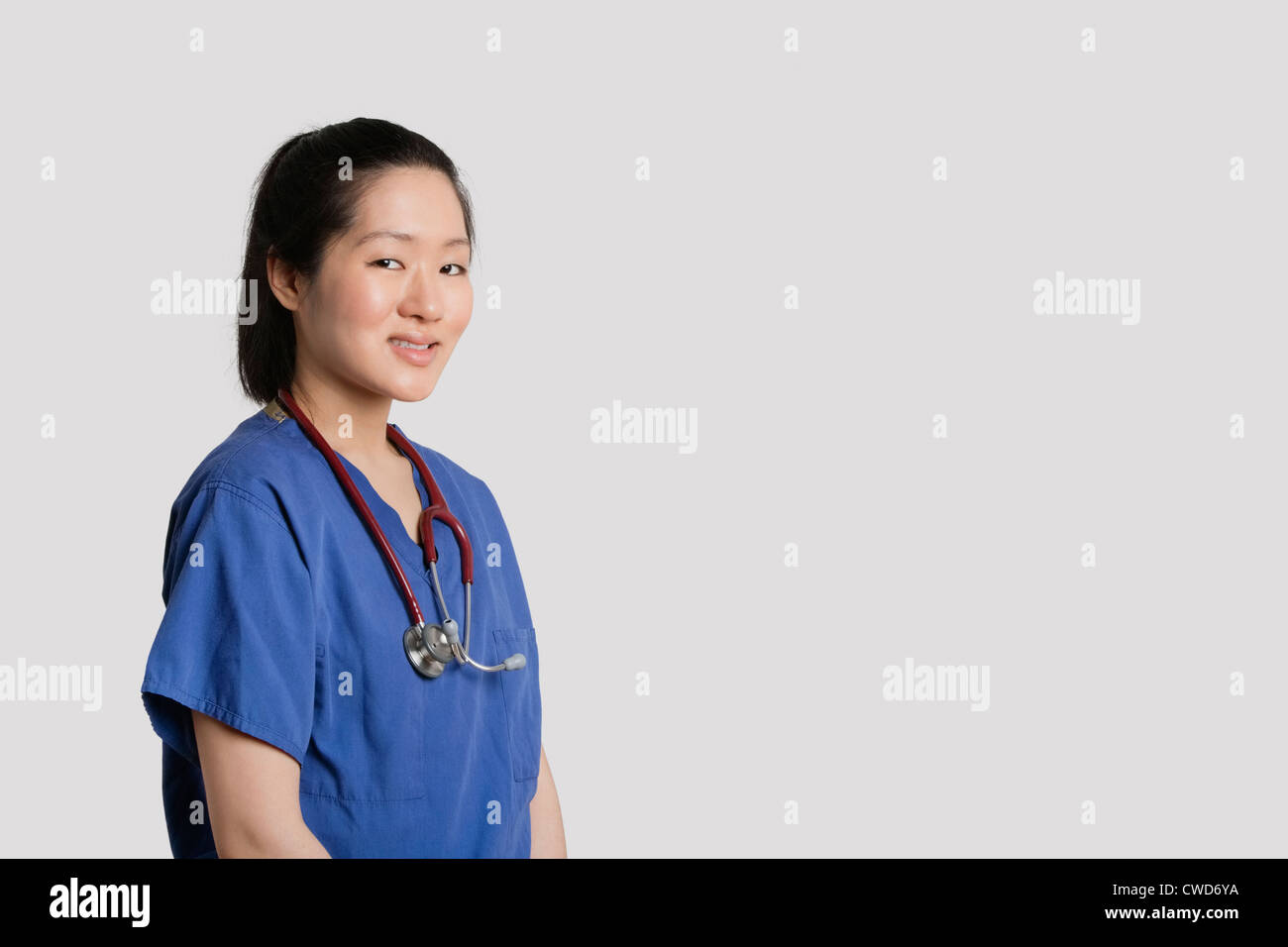 Porträt eines jungen asiatischen weiblichen Chirurgen lächelnd über grauen Hintergrund Stockfoto