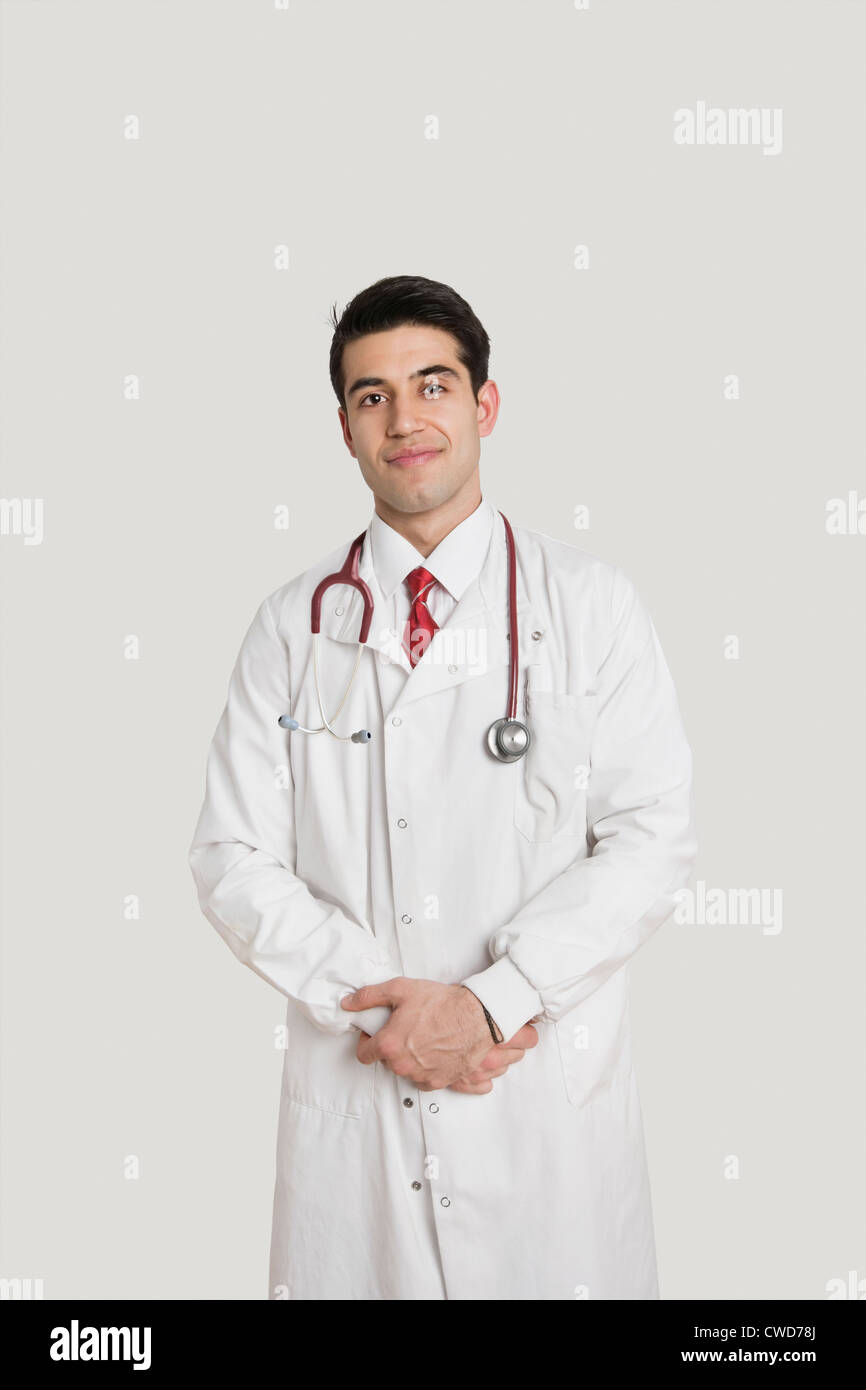 Porträt eines indischen männlichen Arzt lächelnd über grauen Hintergrund Stockfoto