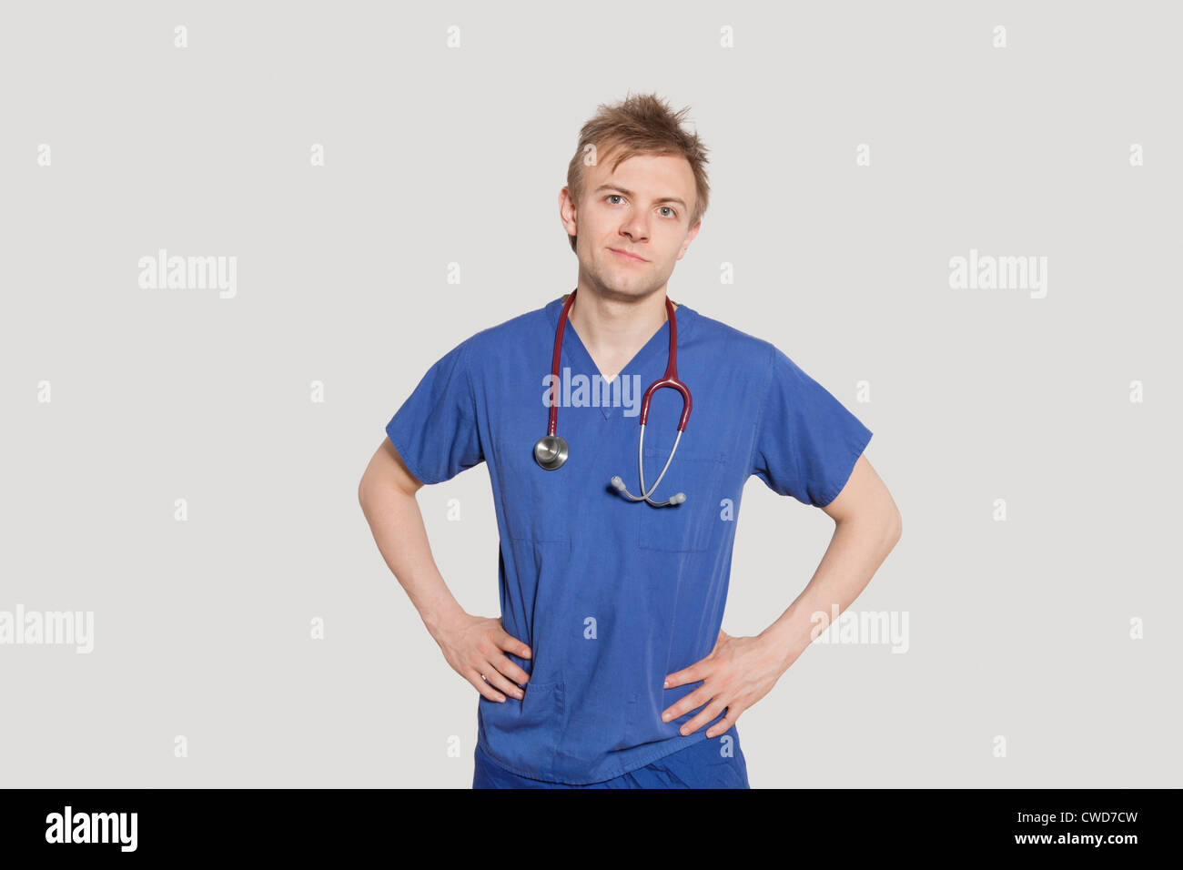 Porträt des männlichen Chirurgen über grauen Hintergrund mit Händen auf den Hüften stehen Stockfoto