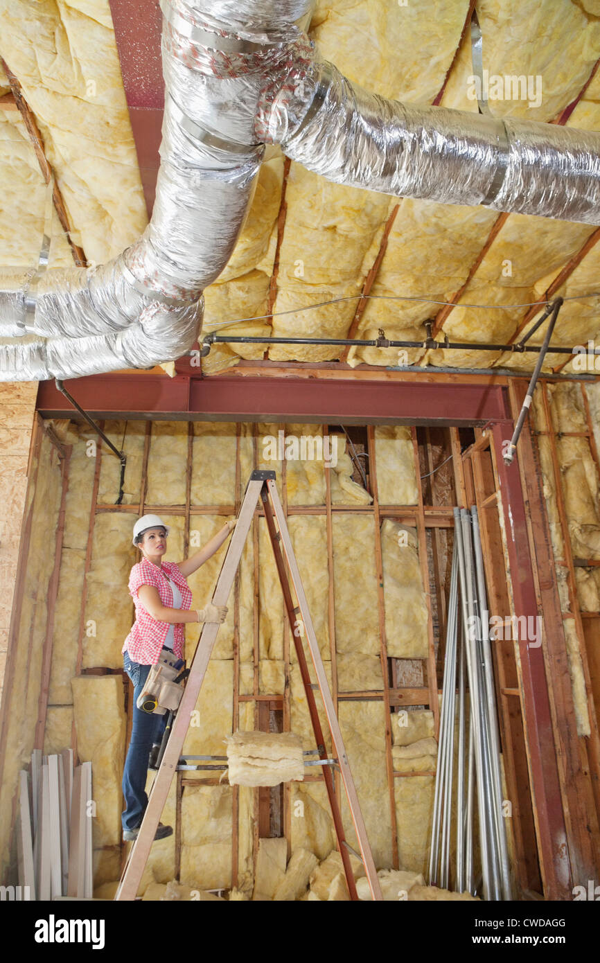 Architektin bewegt die Leiter hinauf, unvollständige Decke zu überprüfen Stockfoto