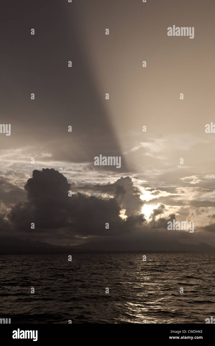 Späten Nachmittag Sonne strahlt durch niedrige Wolken, wie sie in der Nähe der Insel Guadalcanal auf den Salomonen zu sammeln. Stockfoto