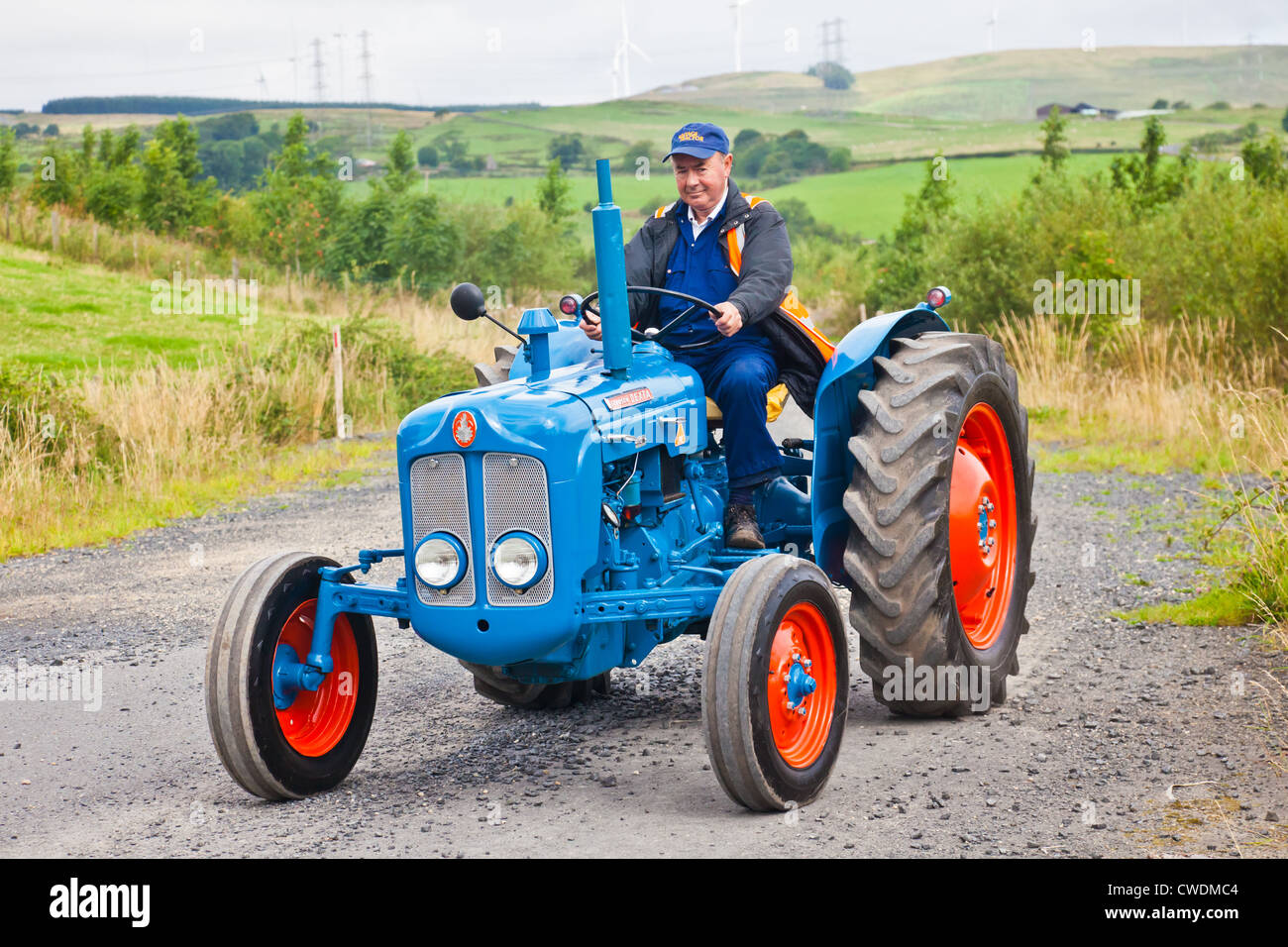 Enthusiasten, die einen blauen Vintage Fordson Dexta 135 Traktor zu fahren, während ein Ayrshire Oldtimer Traktor und Maschine Club Straße Stockfoto