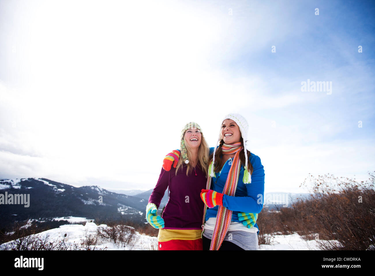 Zwei junge Frauen zum Lachen und Lächeln beim Wandern im Schnee an einem schönen Wintertag in Idaho. Stockfoto