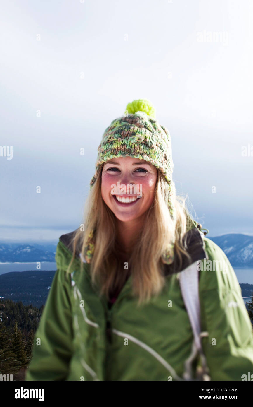 Eine schöne junge Frau lächelnd hält für ein Portrait auf einer Winterwanderung in Idaho. Stockfoto