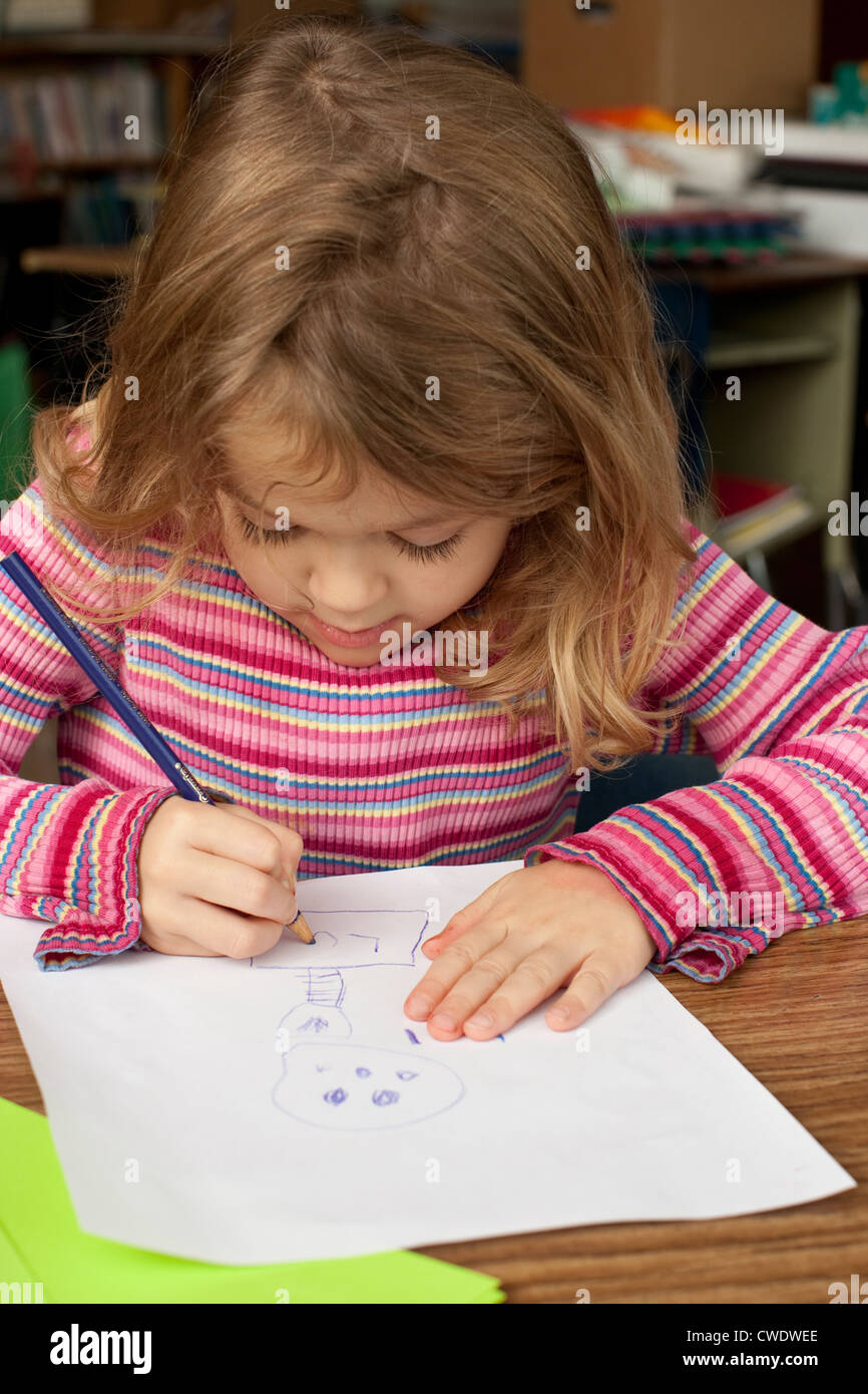 5 Jahre alte weißes Mädchen sitzt am Schreibtisch und Buntstifte auf Papier zeichnen verwendet Stockfoto