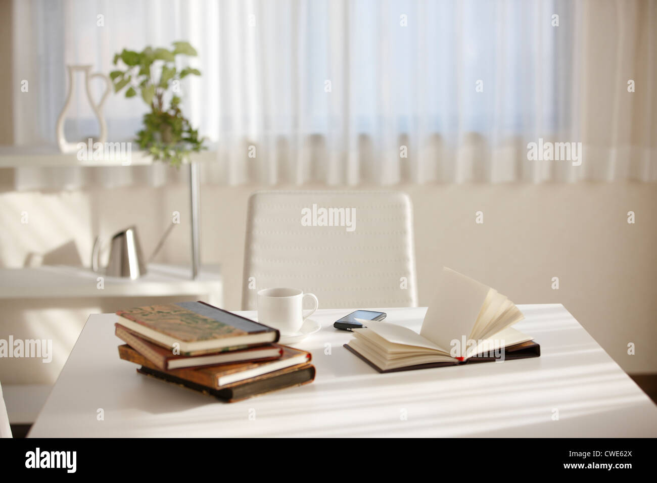 Stapel von Büchern, Teetasse und Handy auf Tisch Stockfoto