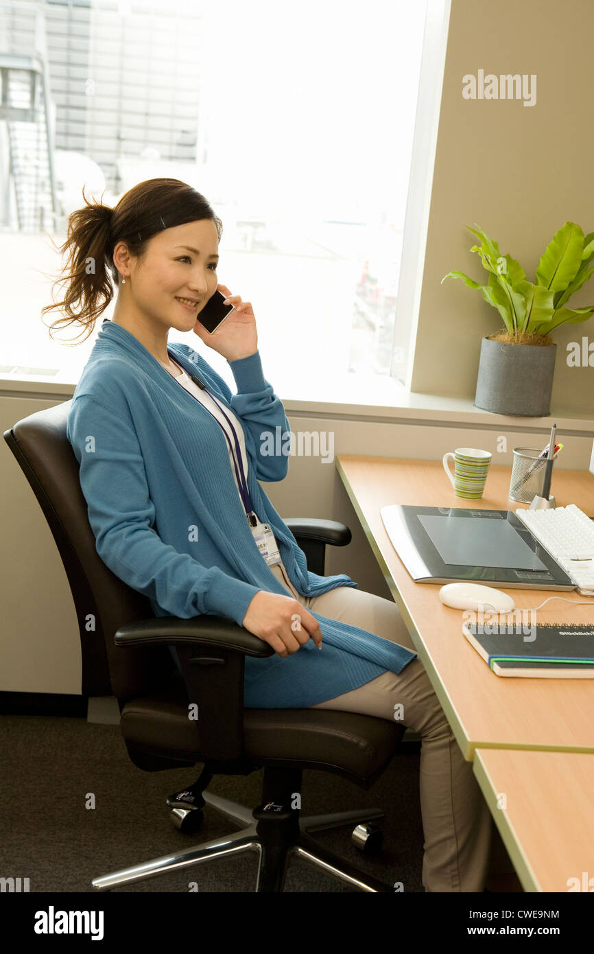 Geschäftsfrau in Freizeitkleidung am Smartphone im Büro sprechen Stockfoto
