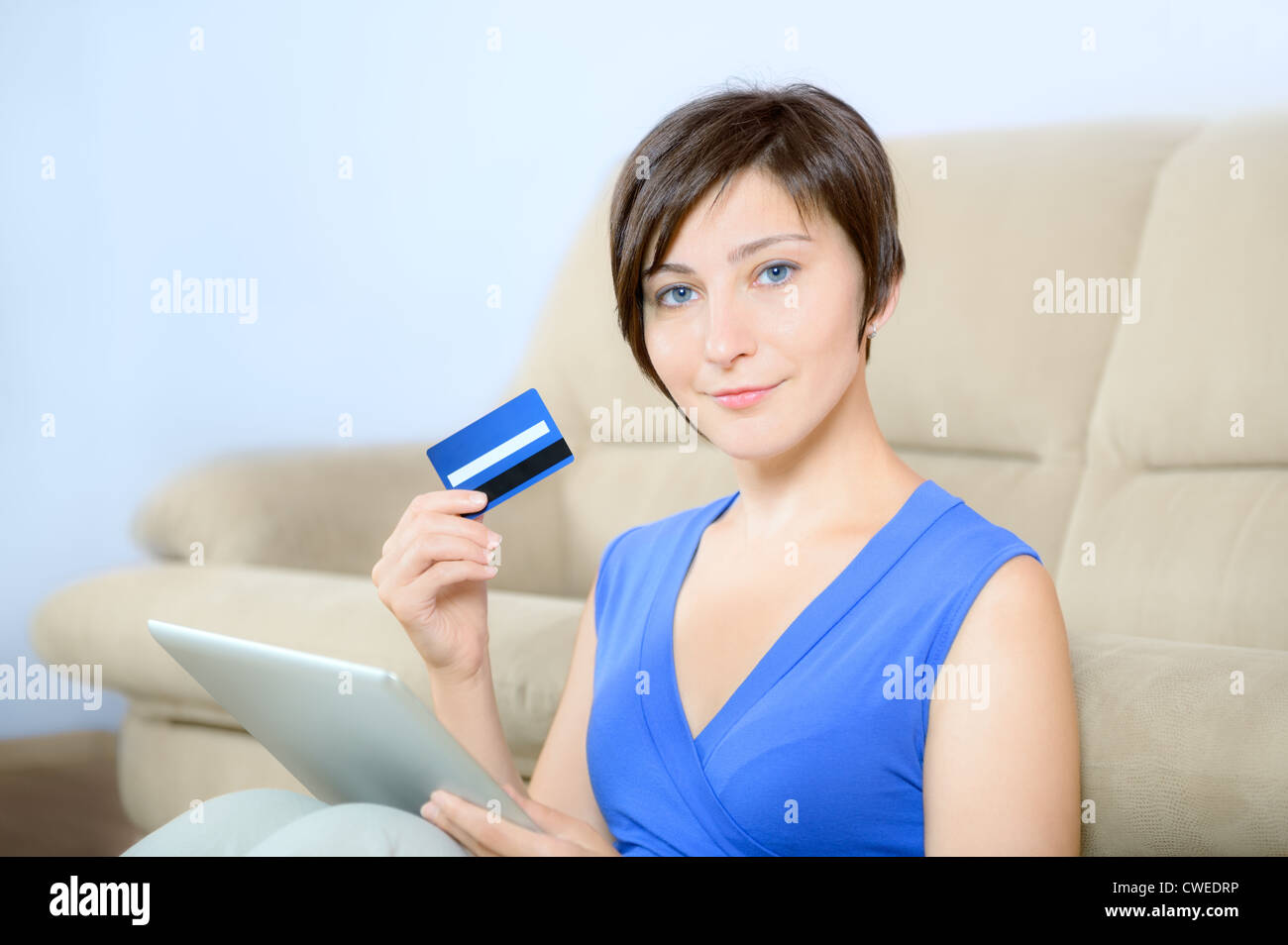 Junge Frau sitzt mit digital-Tablette und halten Sie eine Kreditkarte. Stockfoto