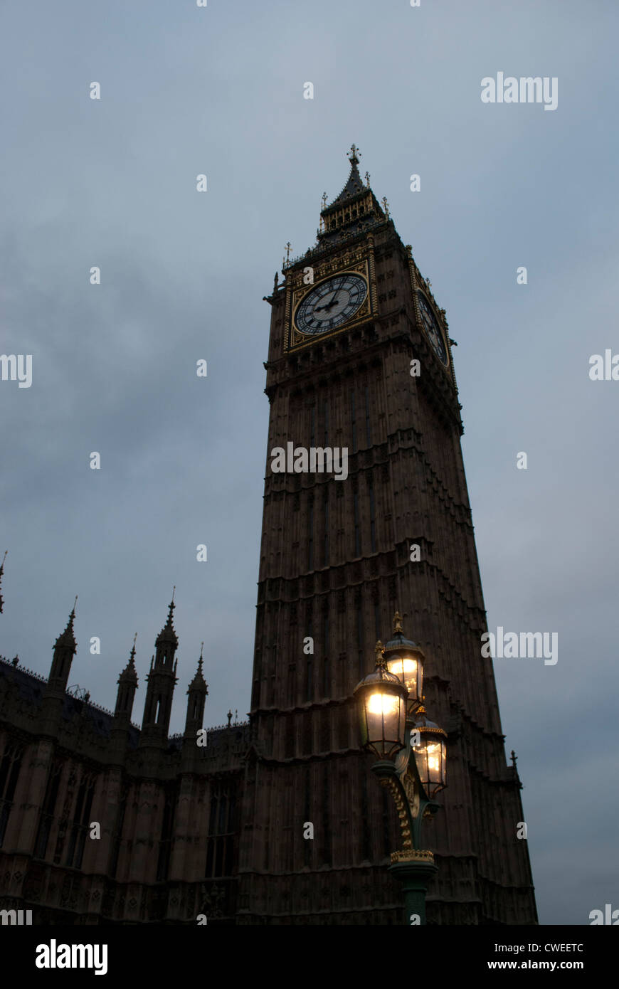 Big Ben und der Palace of Westminster leuchtet dunkel gegen ein bewölkter Himmel mit beleuchteten Straßenlaterne Stockfoto