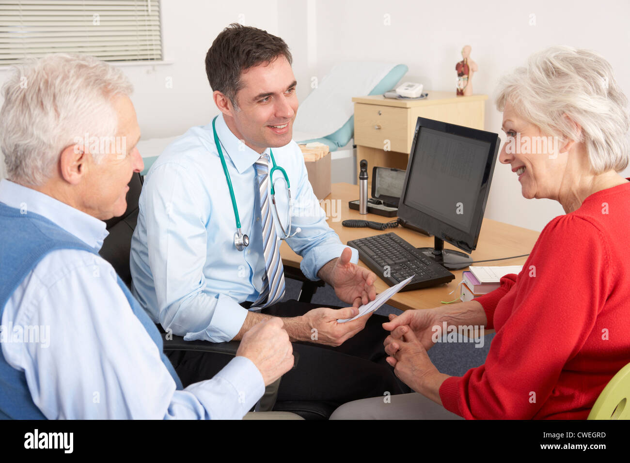 GP von Großbritannien im Gespräch mit älteres Paar in der Chirurgie Stockfoto