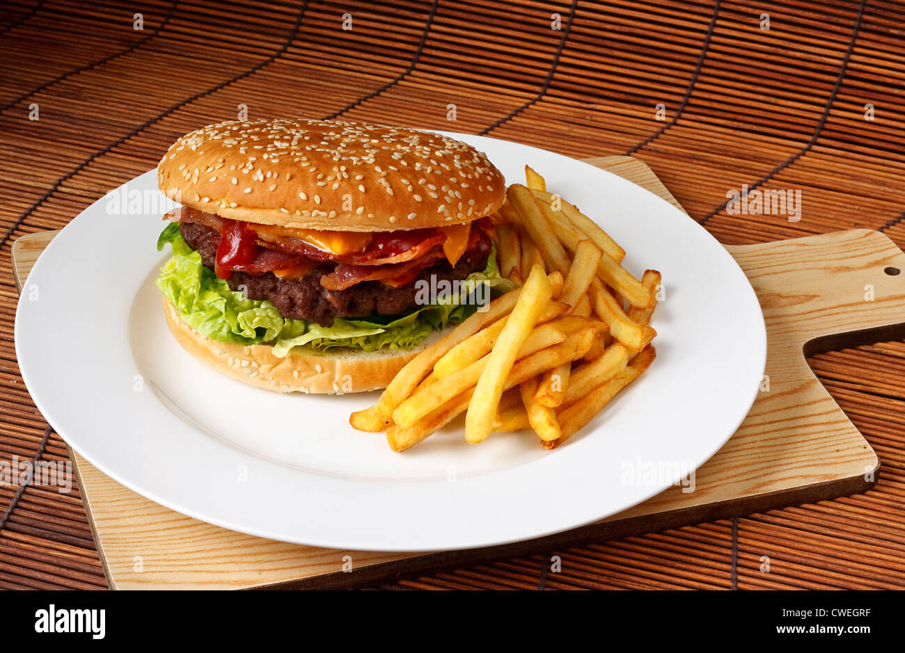 Bacon Cheeseburger mit einem hausgemachten Rindfleisch Patty auf einem Salatbett mit einer Seitenlänge von Pommes frites Stockfoto
