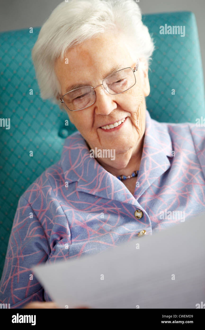 Ältere Frau entspannend In Stuhl lesen schreiben Stockfoto
