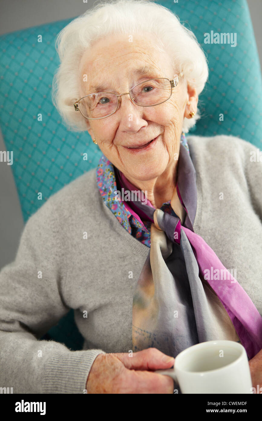 Entspannung In Stuhl mit Heißgetränk Senior Woman Stockfoto