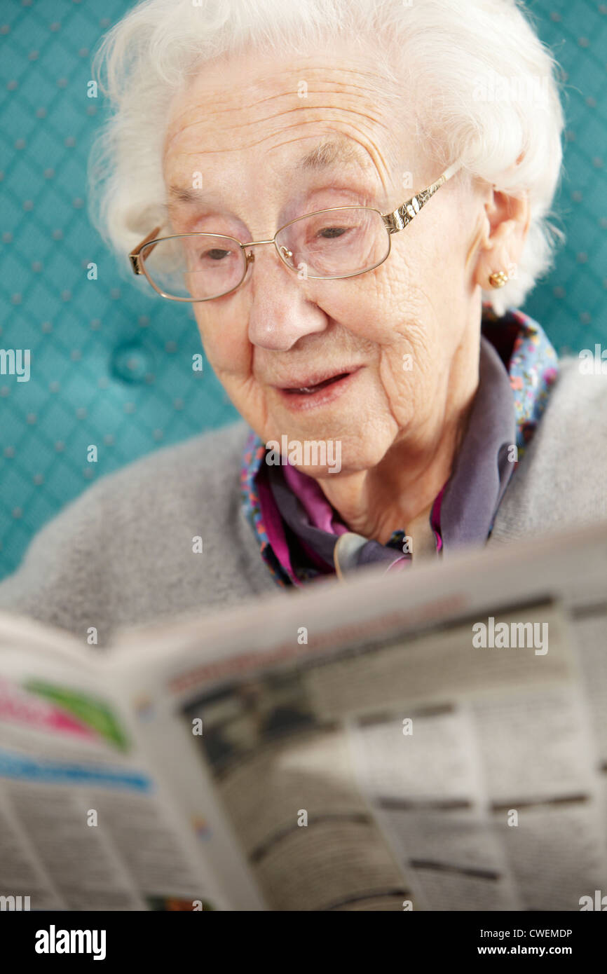 Entspannen im Sessel lesen Zeitung Senior Woman Stockfoto